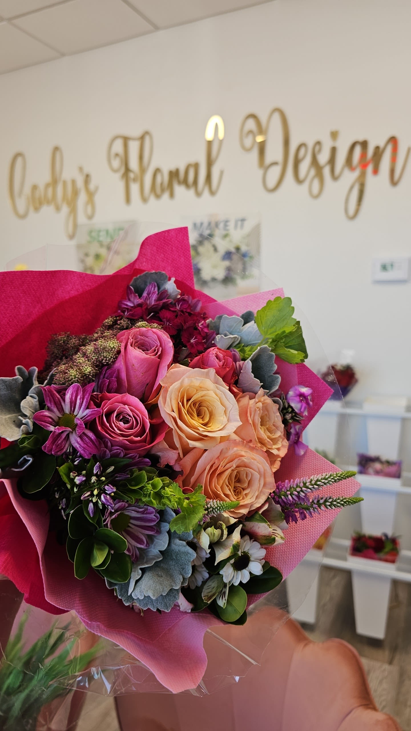 Handheld bouquet of pink, peach, and purple roses with mixed blooms