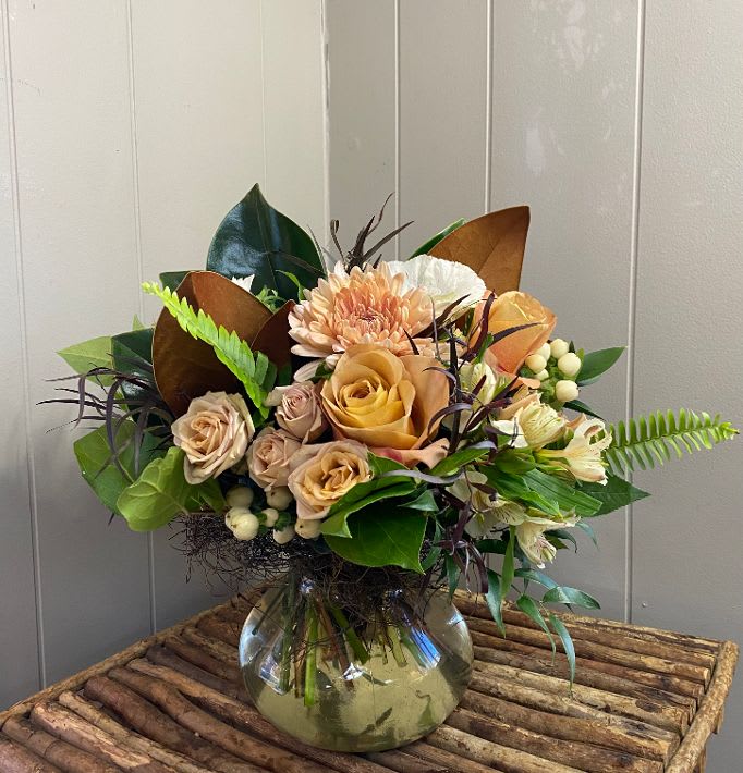 Mixed bouquet of peach and cream flowers in a glass vase