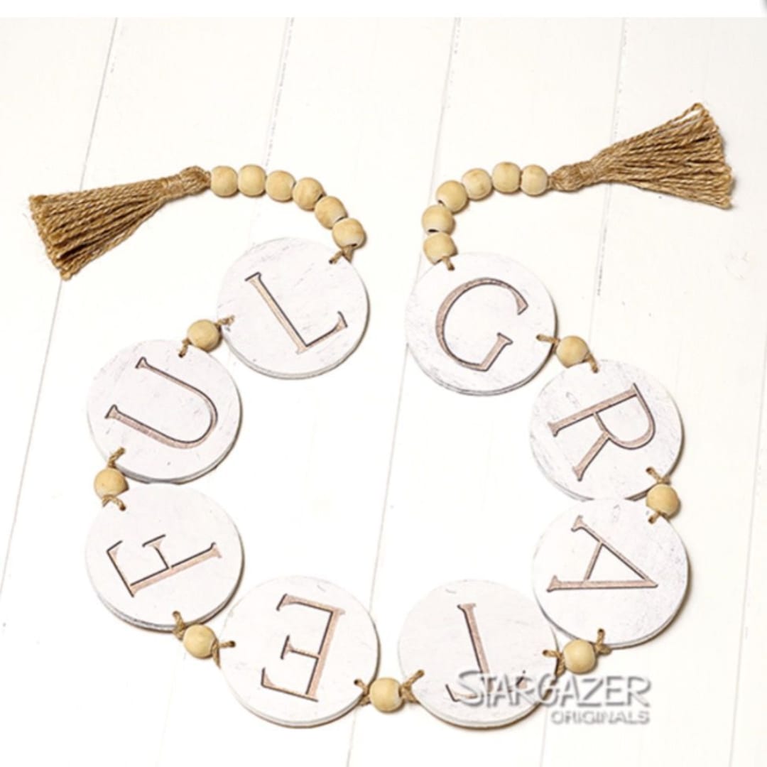 Wood bead garland spelling "UPGRADE" with tassels