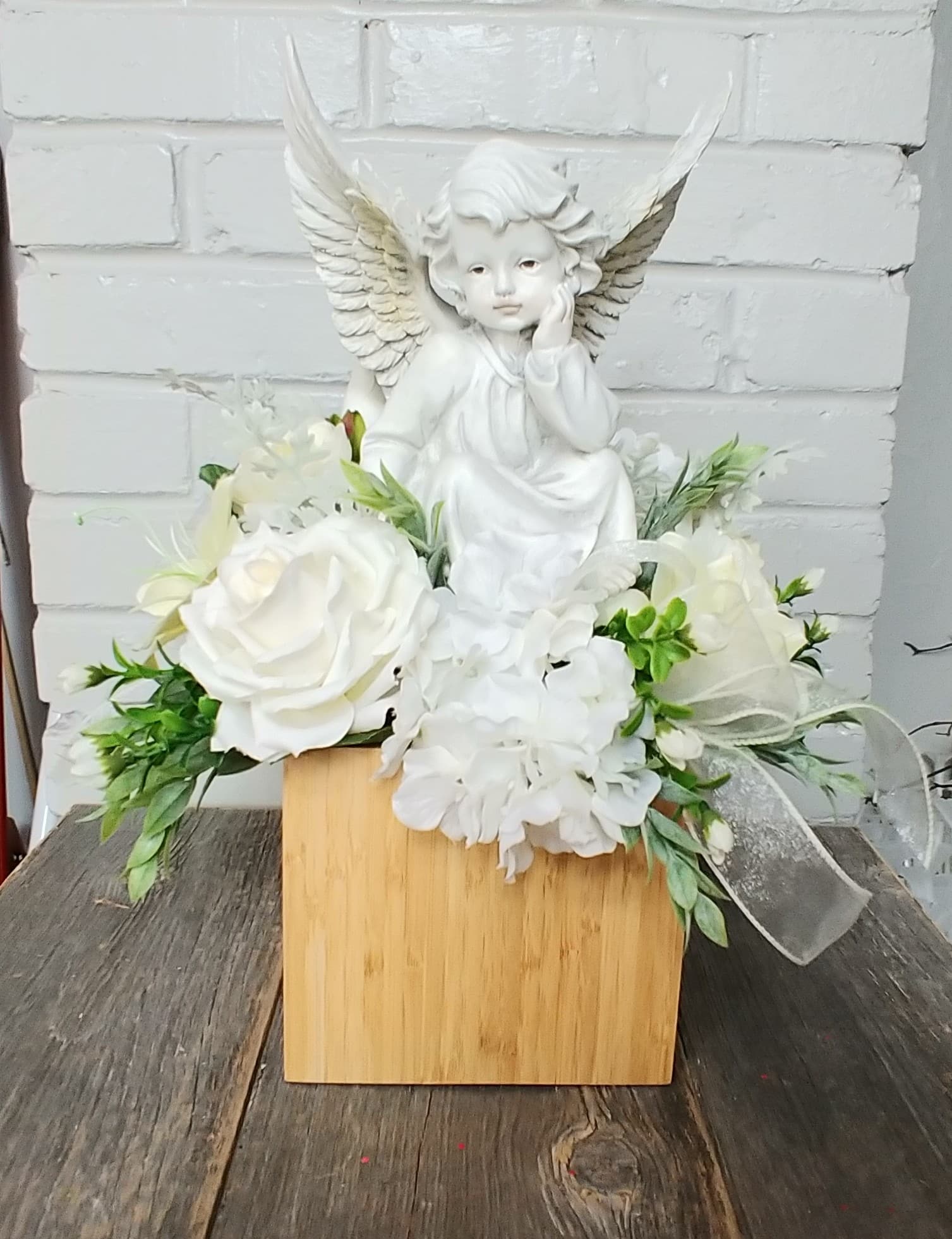 On Angels Wings Silk  - A keepsake angel set in artificial flowers in shades of whites and creams. This product is made from ARTIFICIAL flowers.