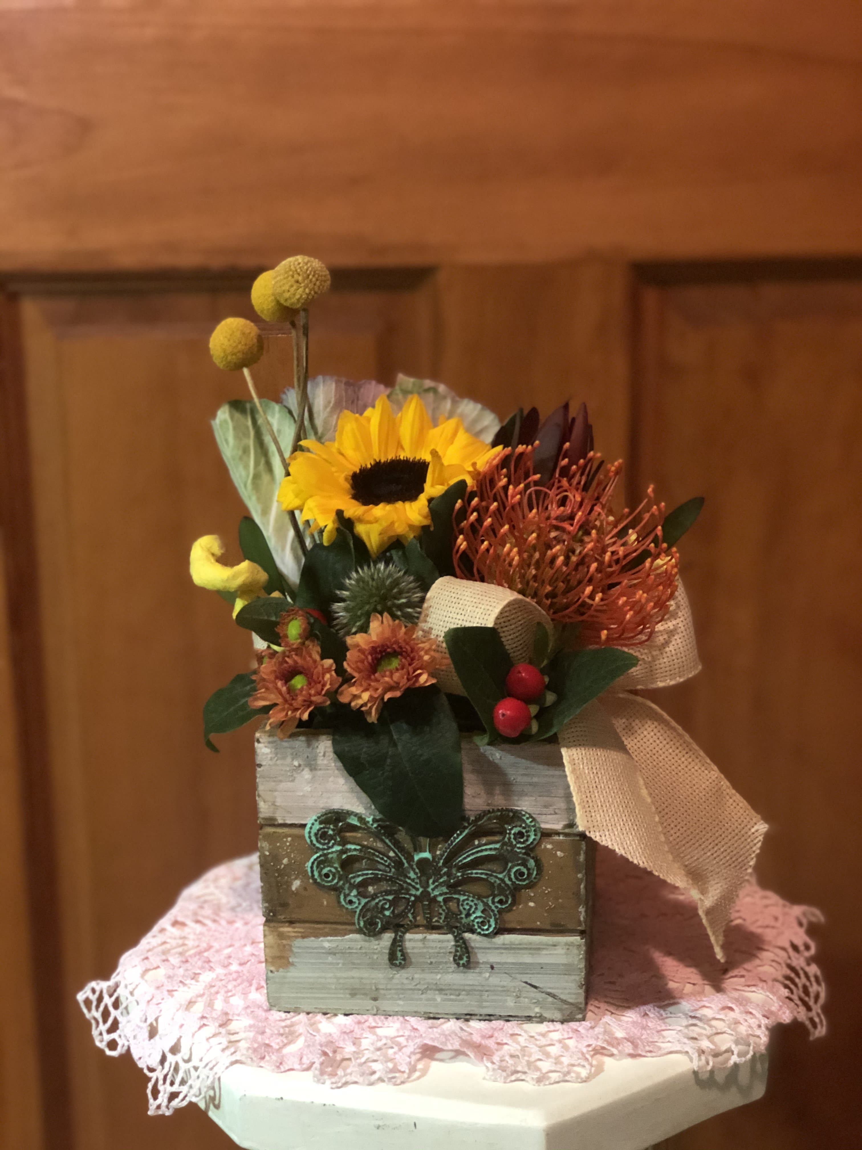 Small floral arrangement in a rustic wooden box with a sunflower and orange blooms