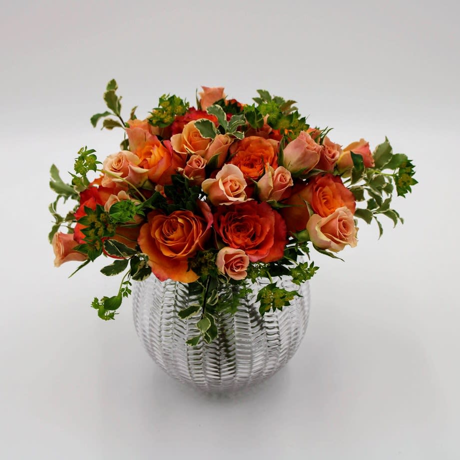 Orange and peach roses arranged in a clear glass vase