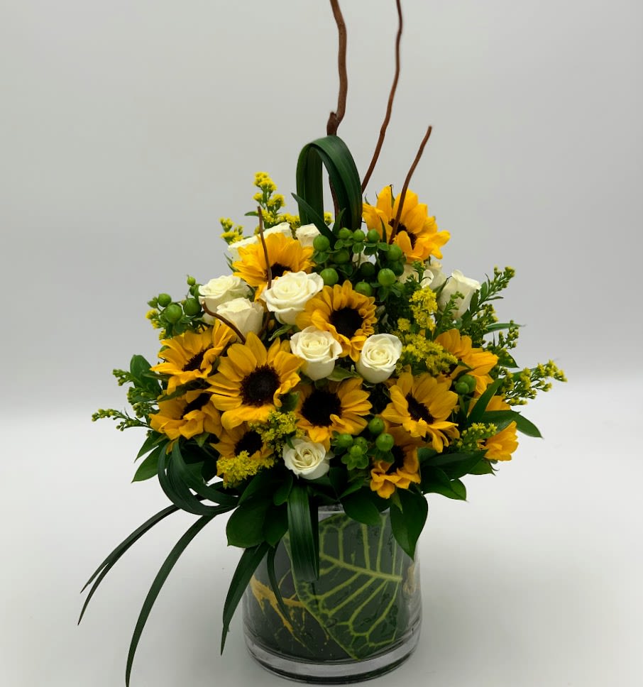 Sunflower and white rose arrangement in a glass vase