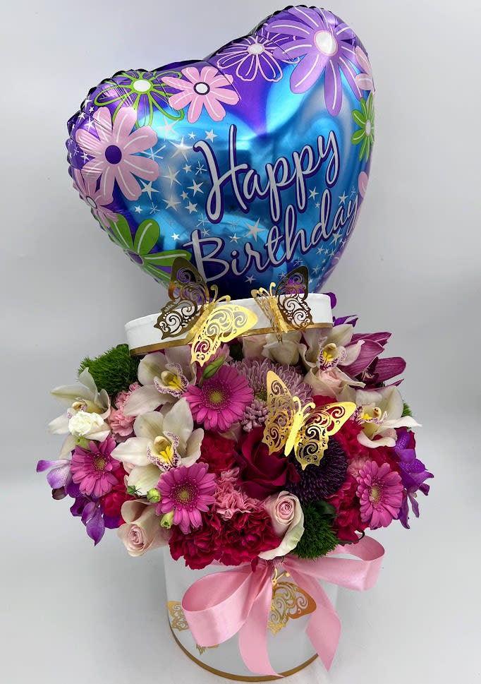 Birthday balloon above a pink and purple flower arrangement in a white box
