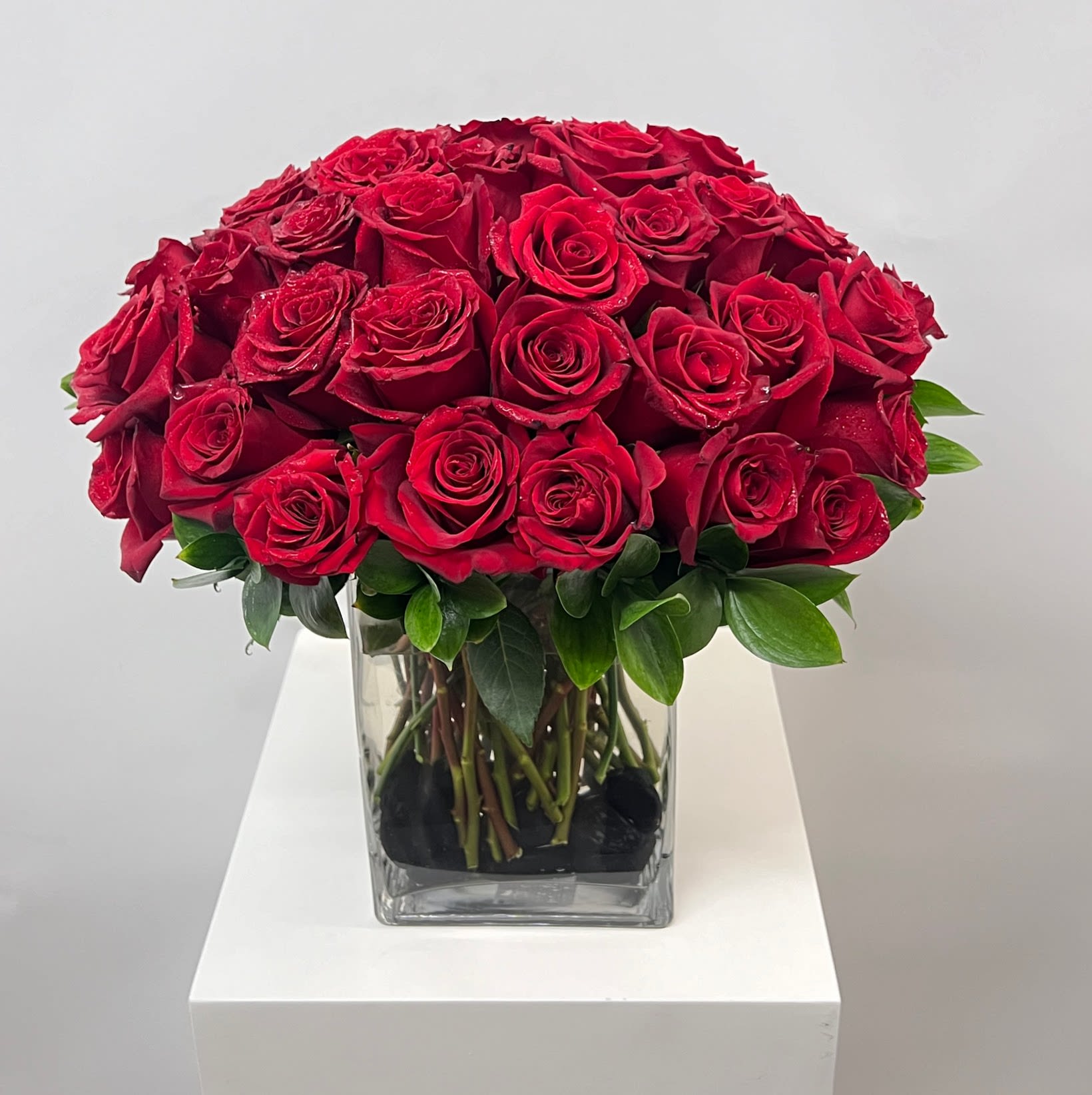Red roses arranged in a clear square glass vase