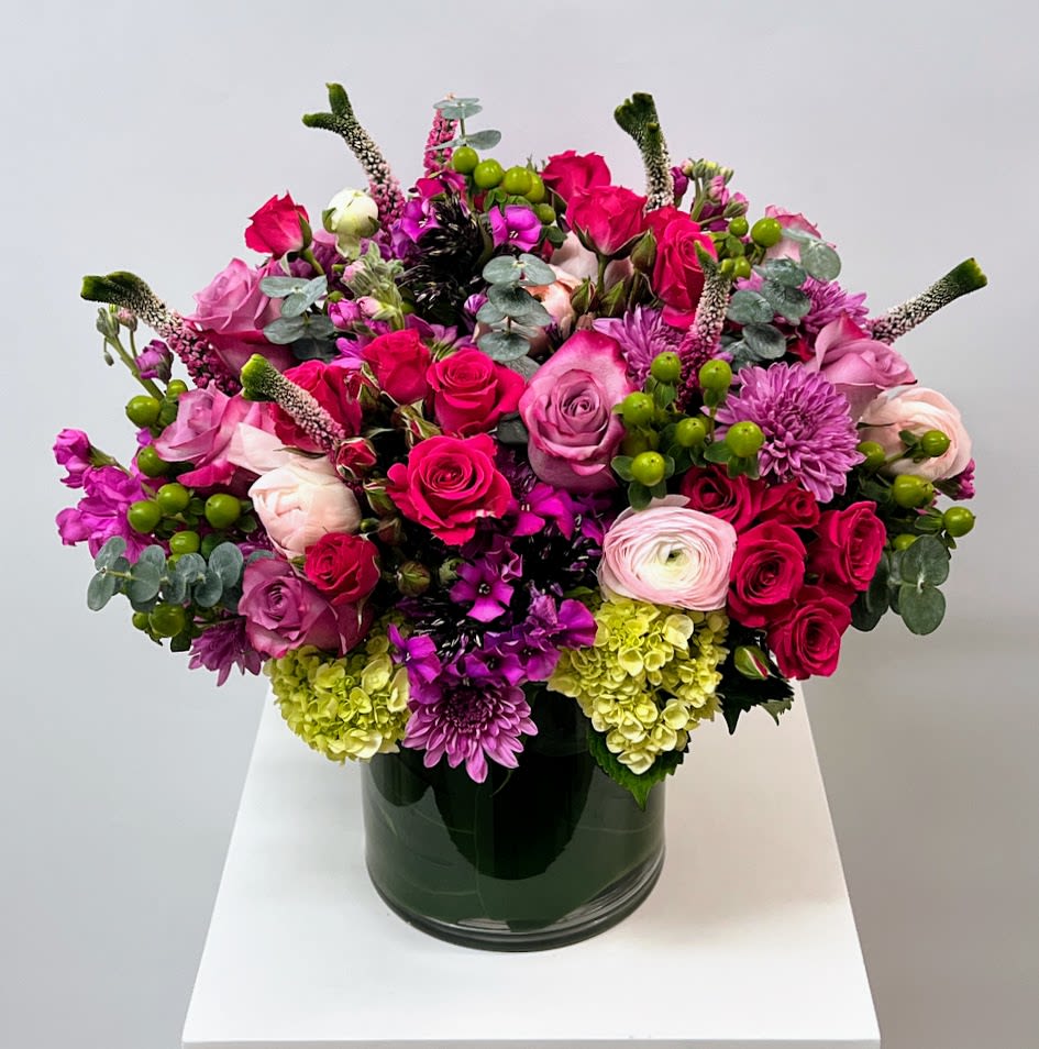 Mixed pink and purple flower arrangement in a dark glass vase
