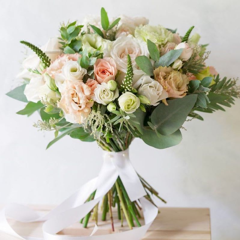 Bouquet of blush and white roses with greenery tied with a white ribbon