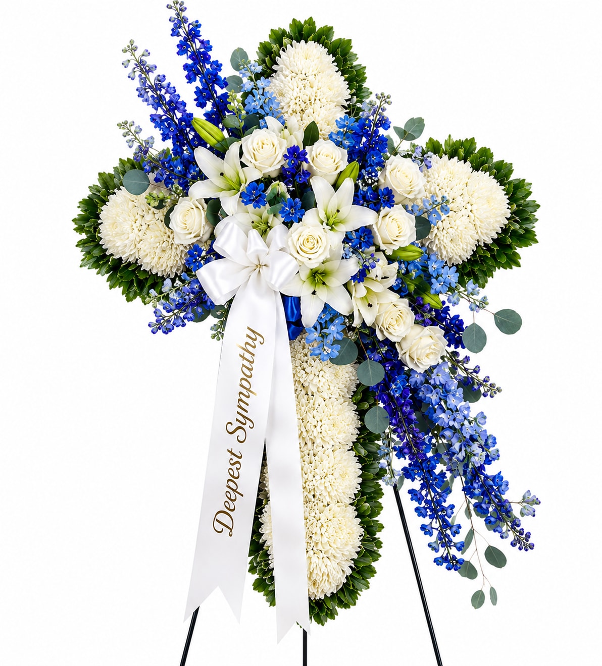 Heavenly Peace Cross - Honor a cherished life with the timeless elegance of the Heavenly Peace Cross. Expertly handcrafted on a standing easel, this striking sympathy tribute features a pristine white chrysanthemum cross beautifully accented with cascading blue delphinium, delicate forget-me-nots, elegant white lilies, premium white roses, and soft eucalyptus foliage.  Finished with a graceful white satin ribbon, this design symbolizes faith, hope, and everlasting love. The serene combination of crisp white blooms and vibrant blue accents offers a comforting expression of sympathy, making it a meaningful choice for funeral services, memorial ceremonies, church tributes, or celebrations of life.  Each arrangement is carefully designed using fresh, high-quality flowers to create a lasting impression of peace, remembrance, and compassion.  Key Features White chrysanthemum cross with lush green edging Premium white roses and fragrant white lilies Vibrant blue delphinium and delicate blue accent flowers Accented with fresh eucalyptus and seasonal greenery Displayed on a sturdy standing easel with an elegant sympathy ribbon Ideal for funeral homes, churches, memorial services, and graveside tributes