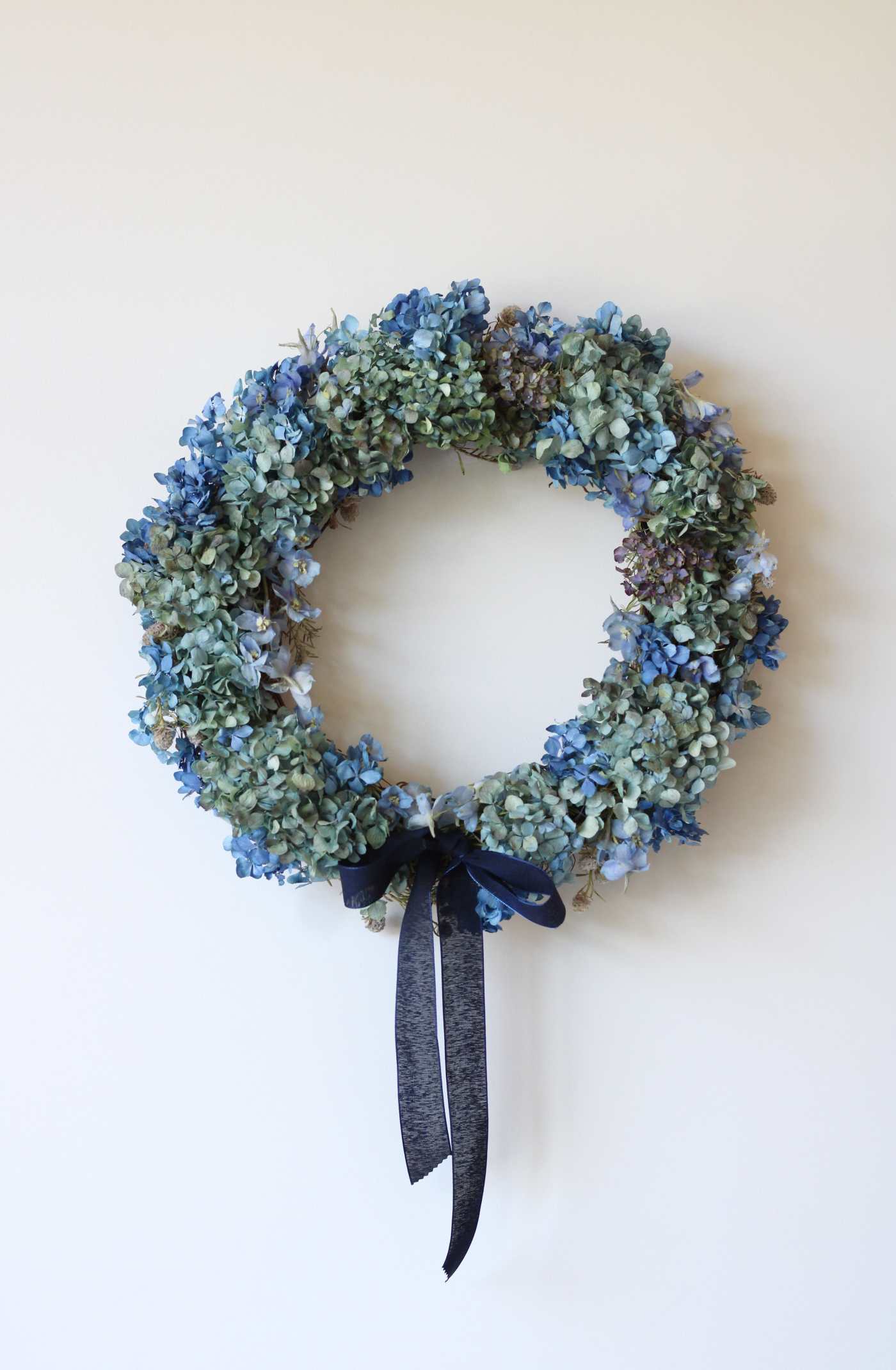 Blue and green floral wreath with a dark ribbon bow