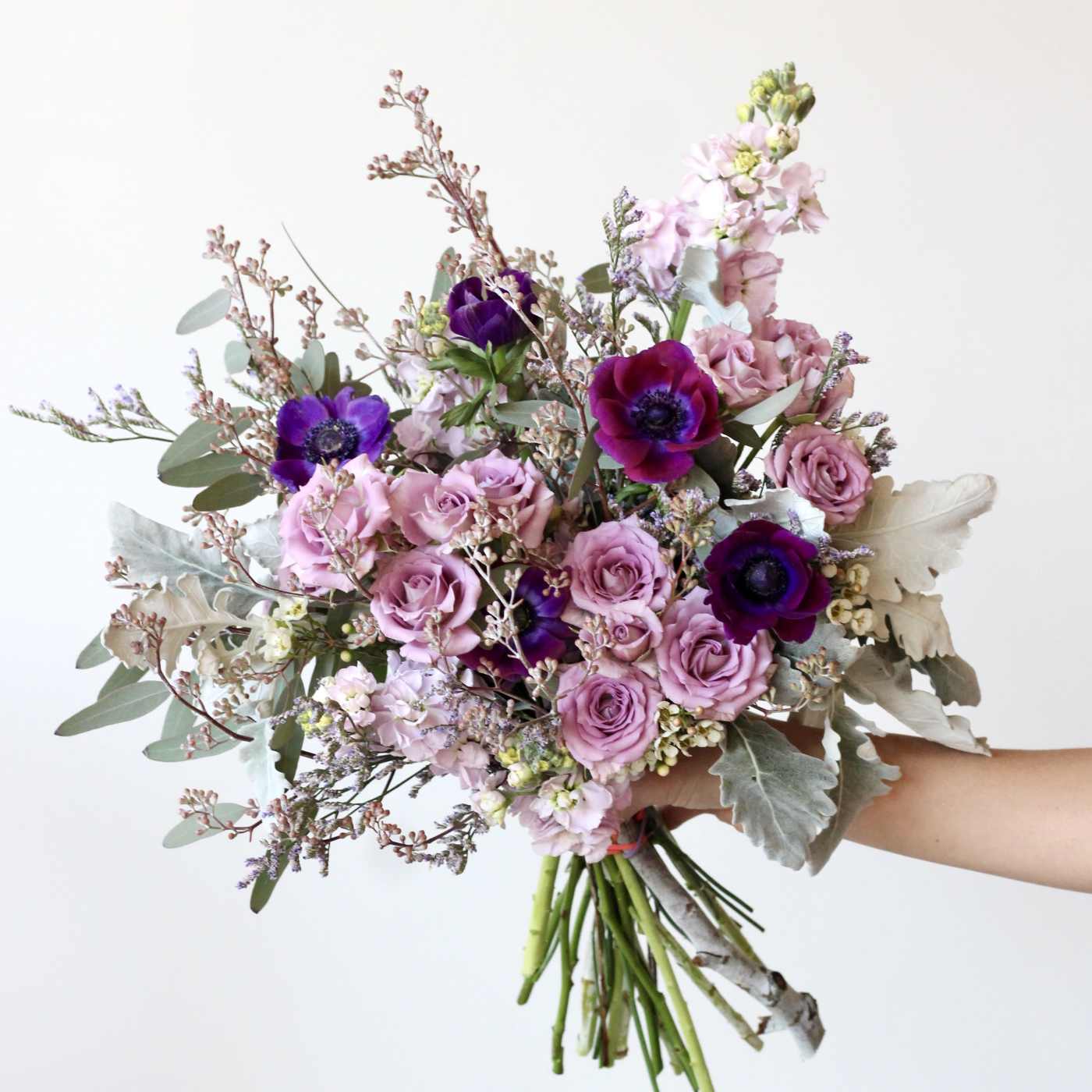 Hand-tied bouquet of pink and purple flowers with silvery foliage