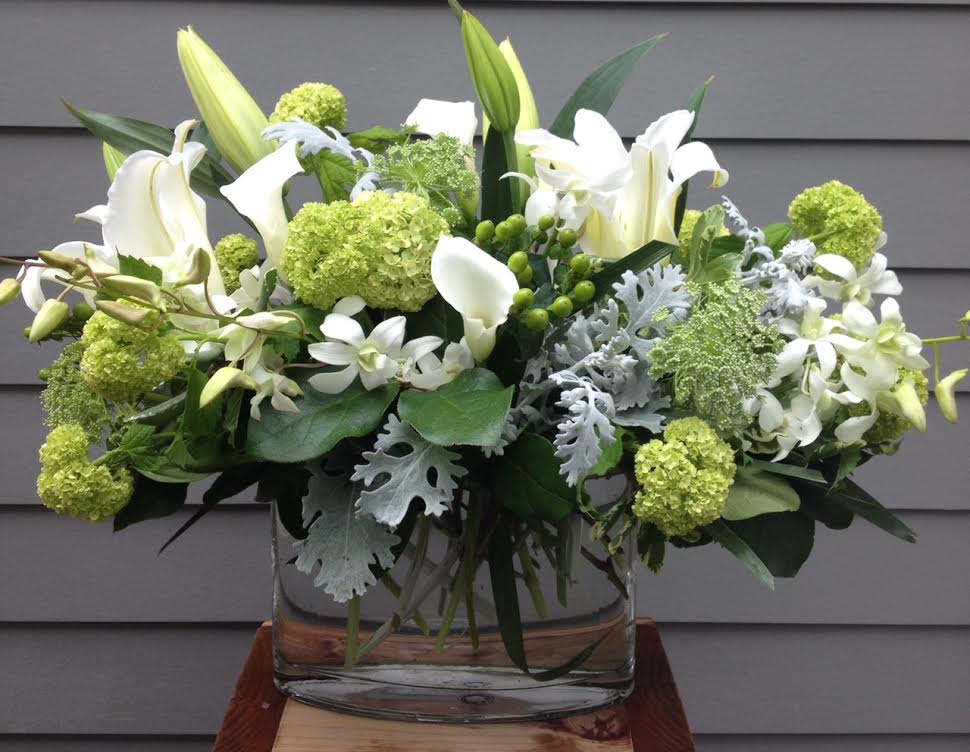 White lilies and green blooms in a clear glass vase