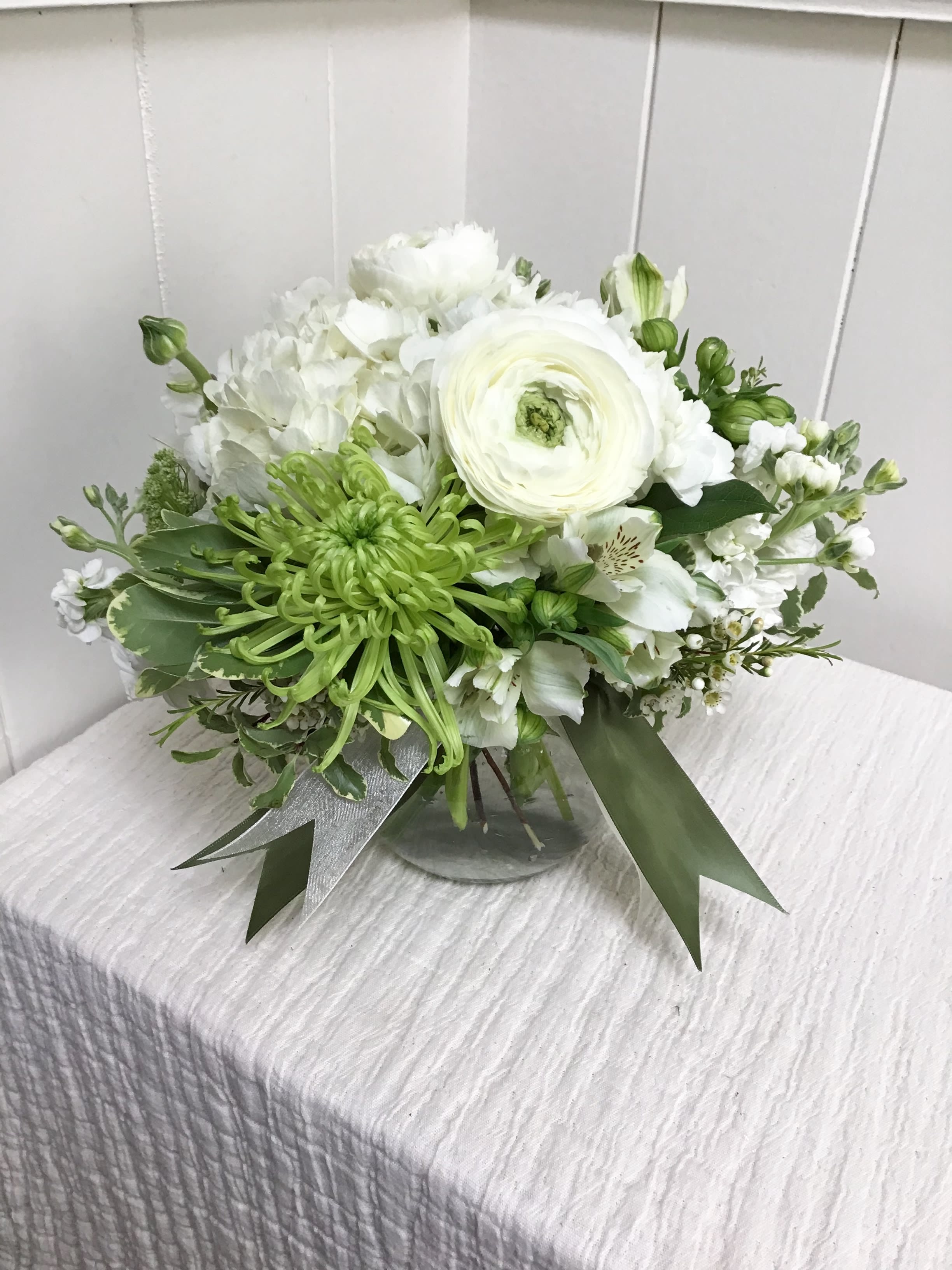 White and green floral arrangement in a glass vase
