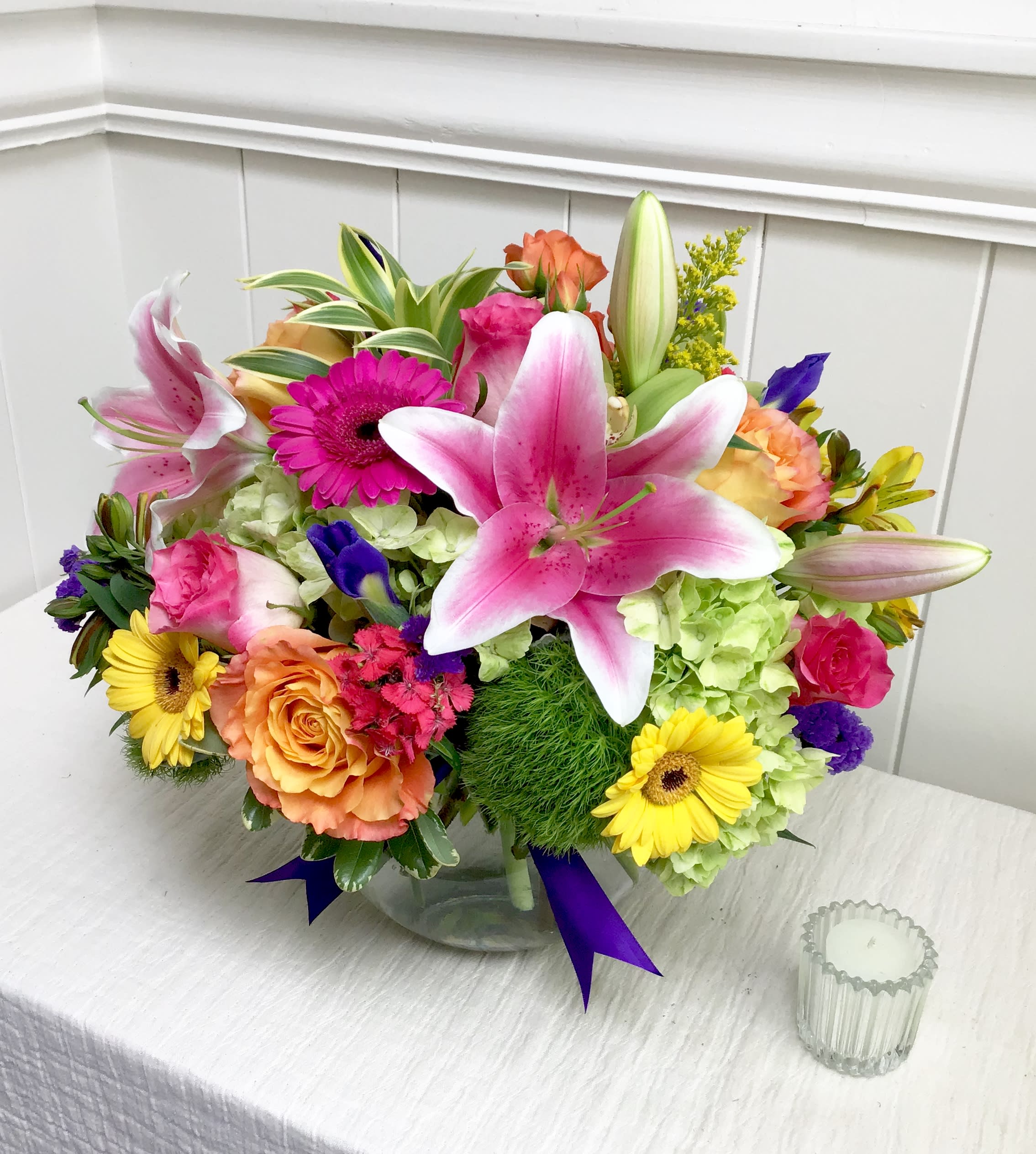 Mixed bouquet in a clear glass vase with pink lilies, roses, and gerbera daisies