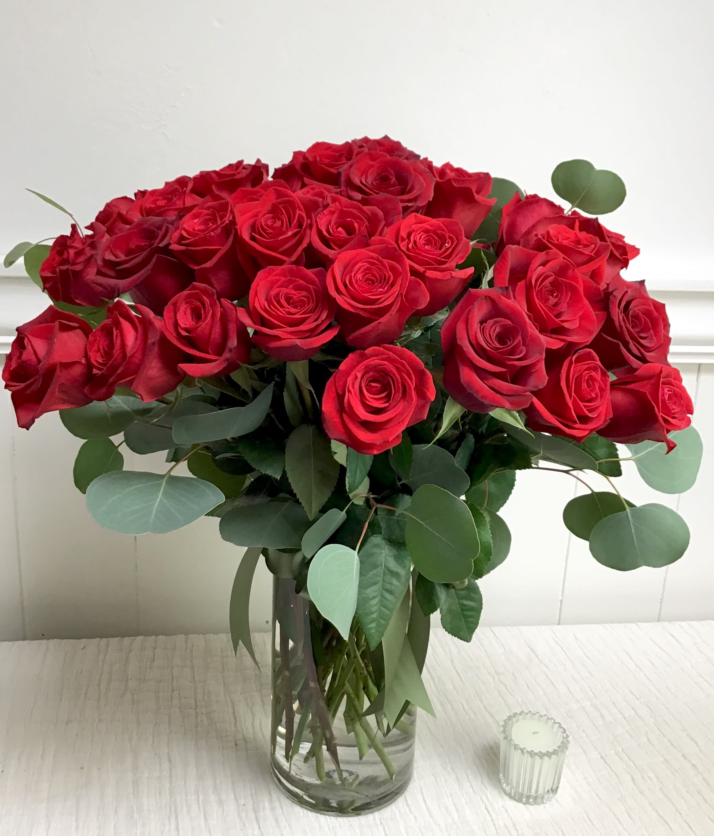 Bouquet of red roses in a clear glass vase with eucalyptus