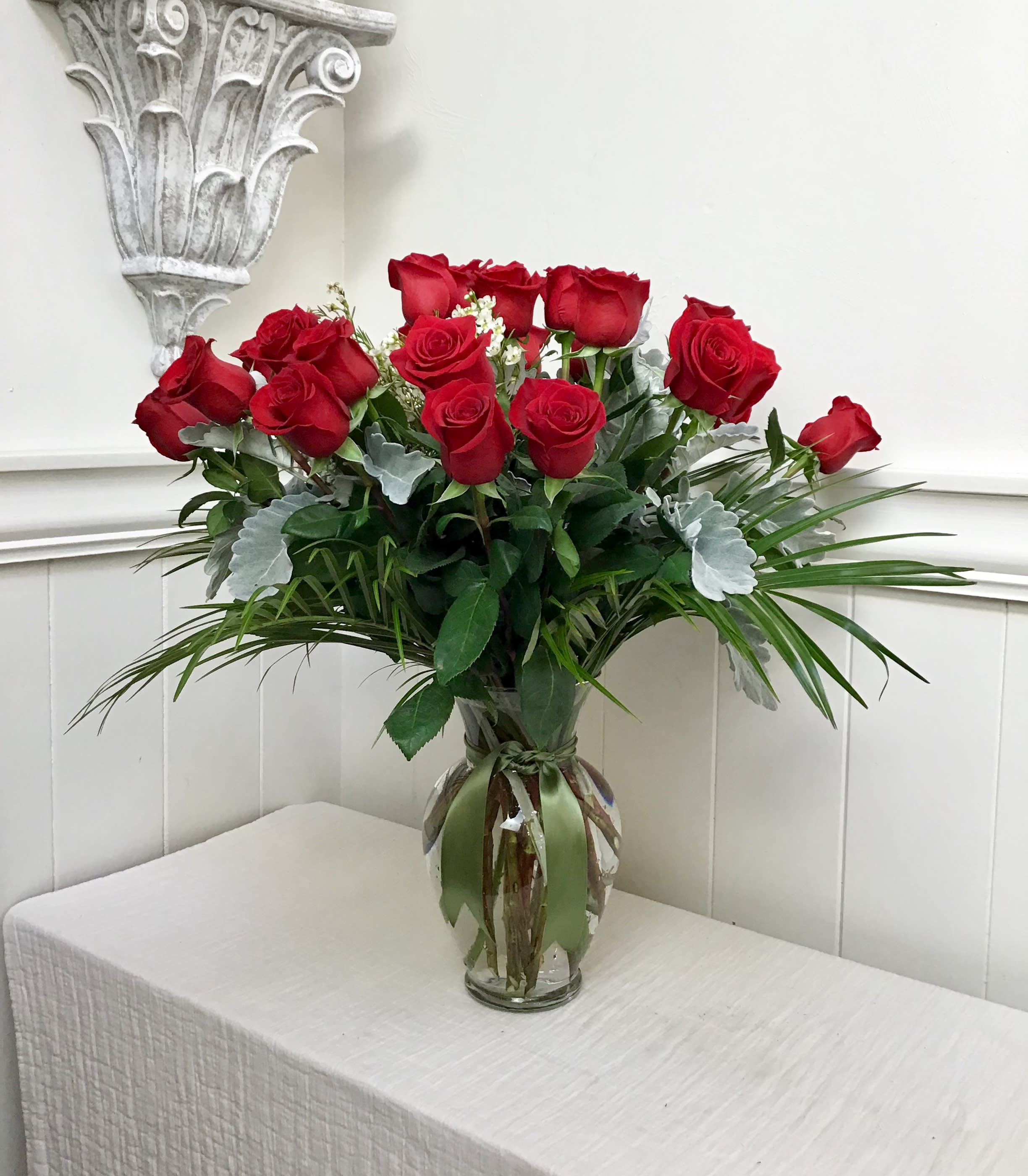 Red roses arranged in a clear glass vase with greenery