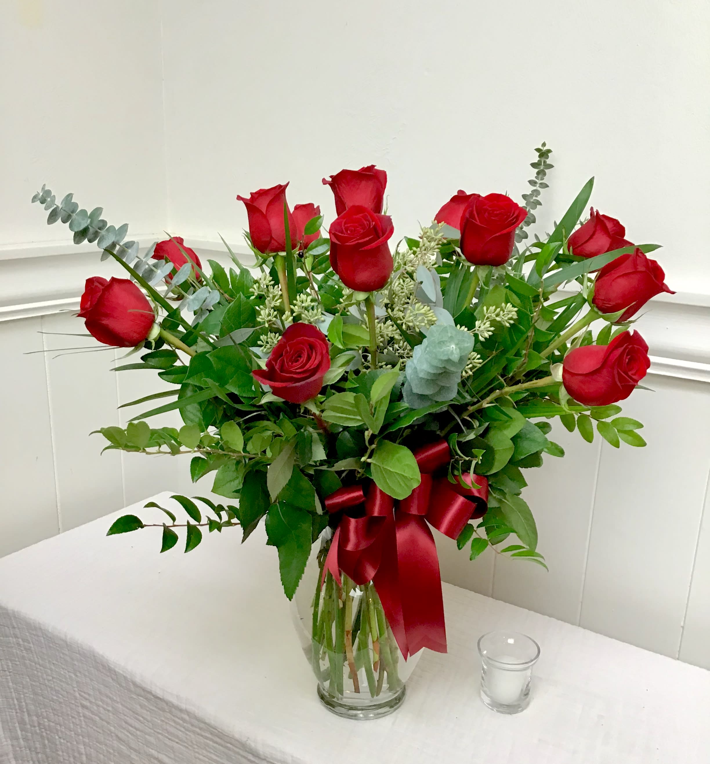 Bouquet of red roses in a clear glass vase with a red ribbon