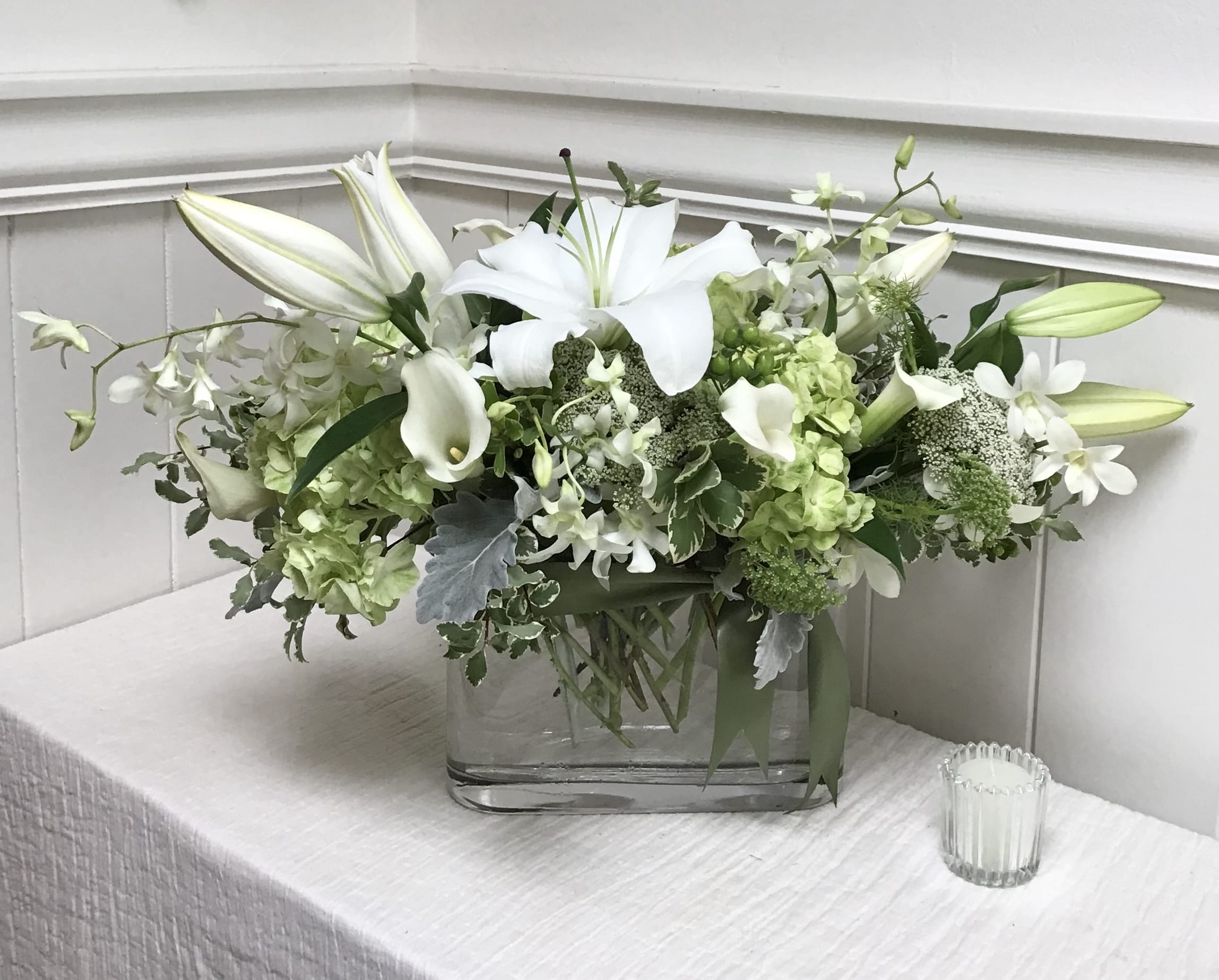 White lilies and green-white flowers in a clear glass vase