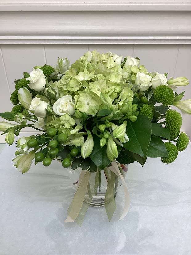 Green and white bouquet in a glass vase with ribbon