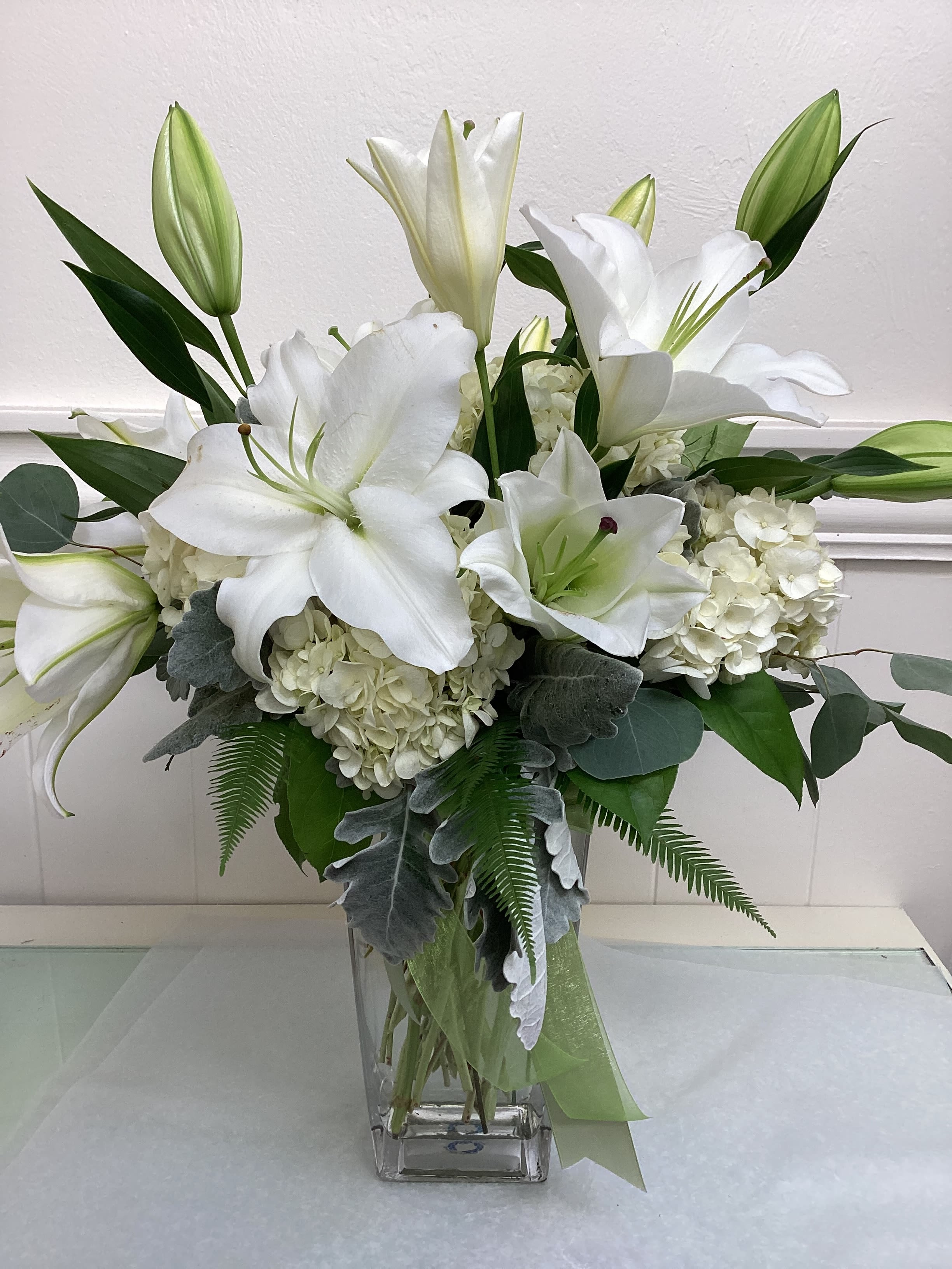 White lilies and hydrangeas arranged in a clear glass vase