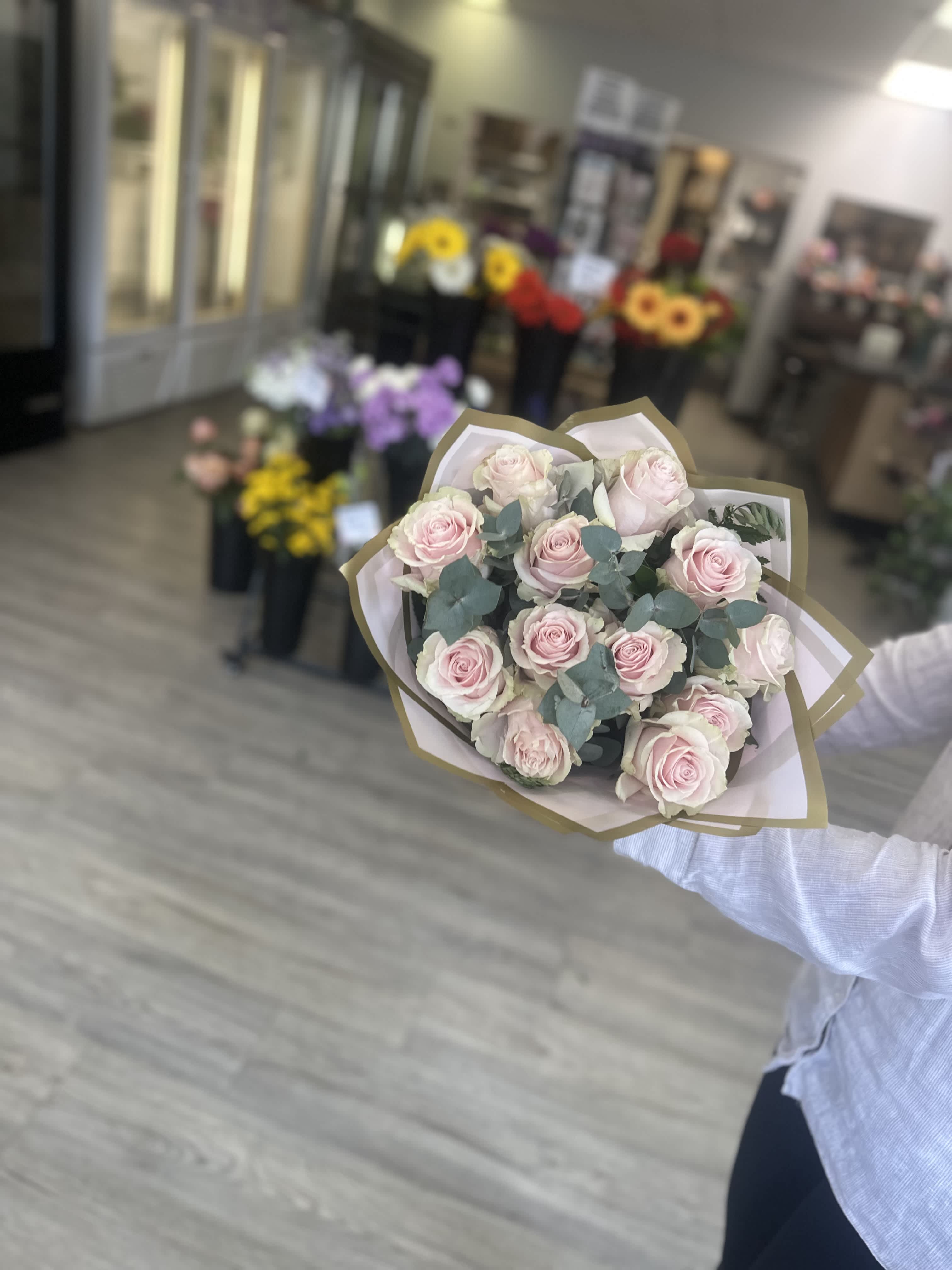 Handheld bouquet of pale pink roses wrapped in paper