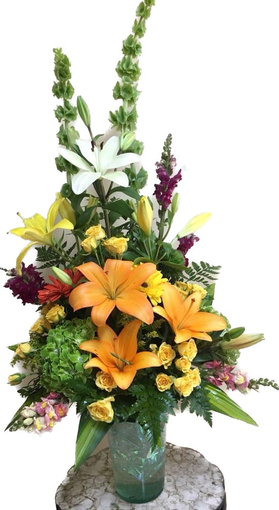 Tall mixed flower arrangement with lilies, roses, and snapdragons in a glass vase