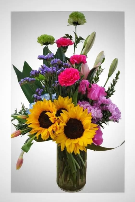 Mixed bouquet with sunflowers, carnations, and lilies in a glass vase