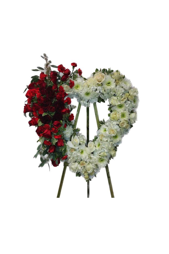 Heart-shaped funeral wreath with red and white flowers on a stand