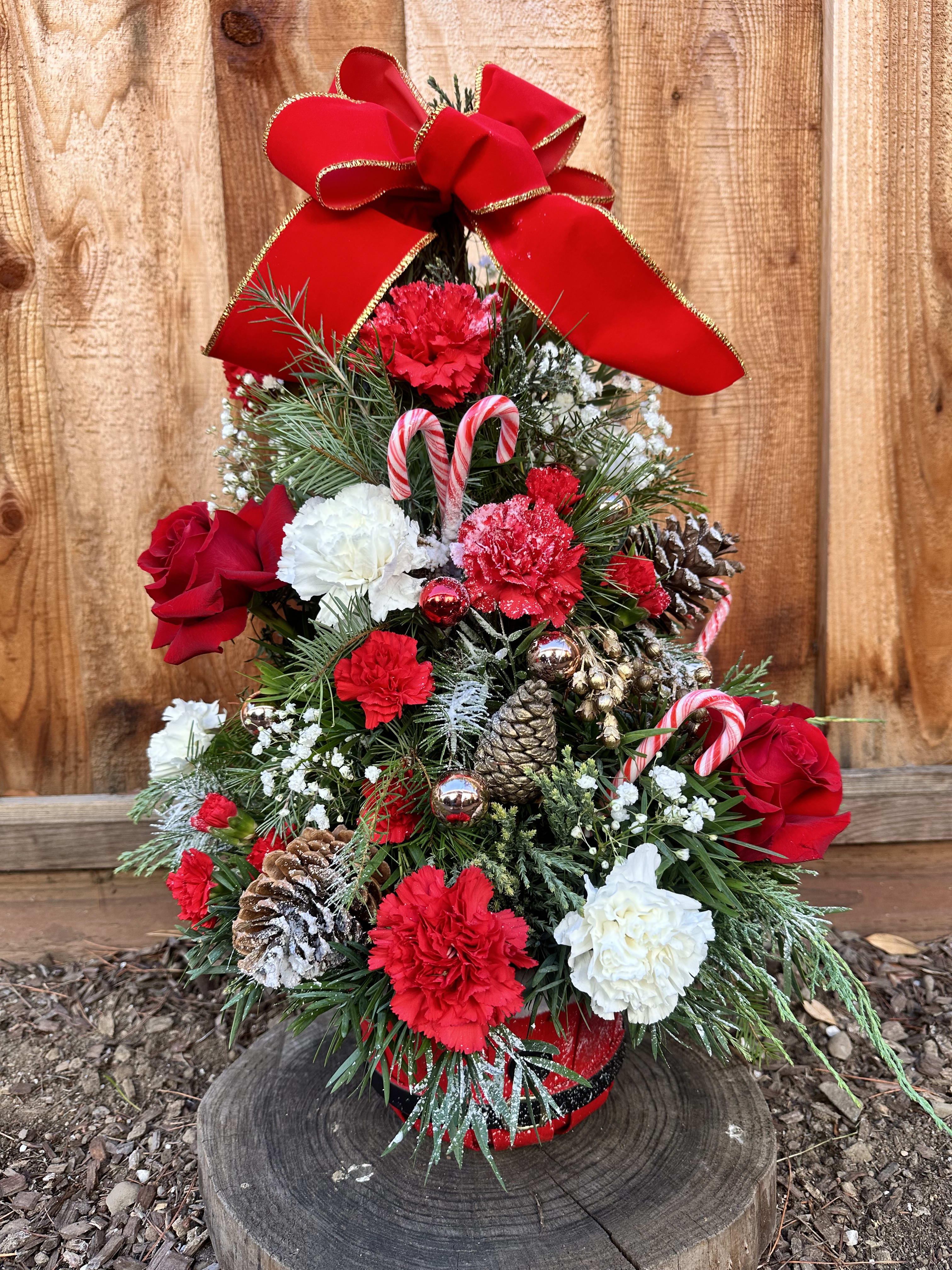Christmas tree arrangement with red and white flowers, candy canes, and a large red bow