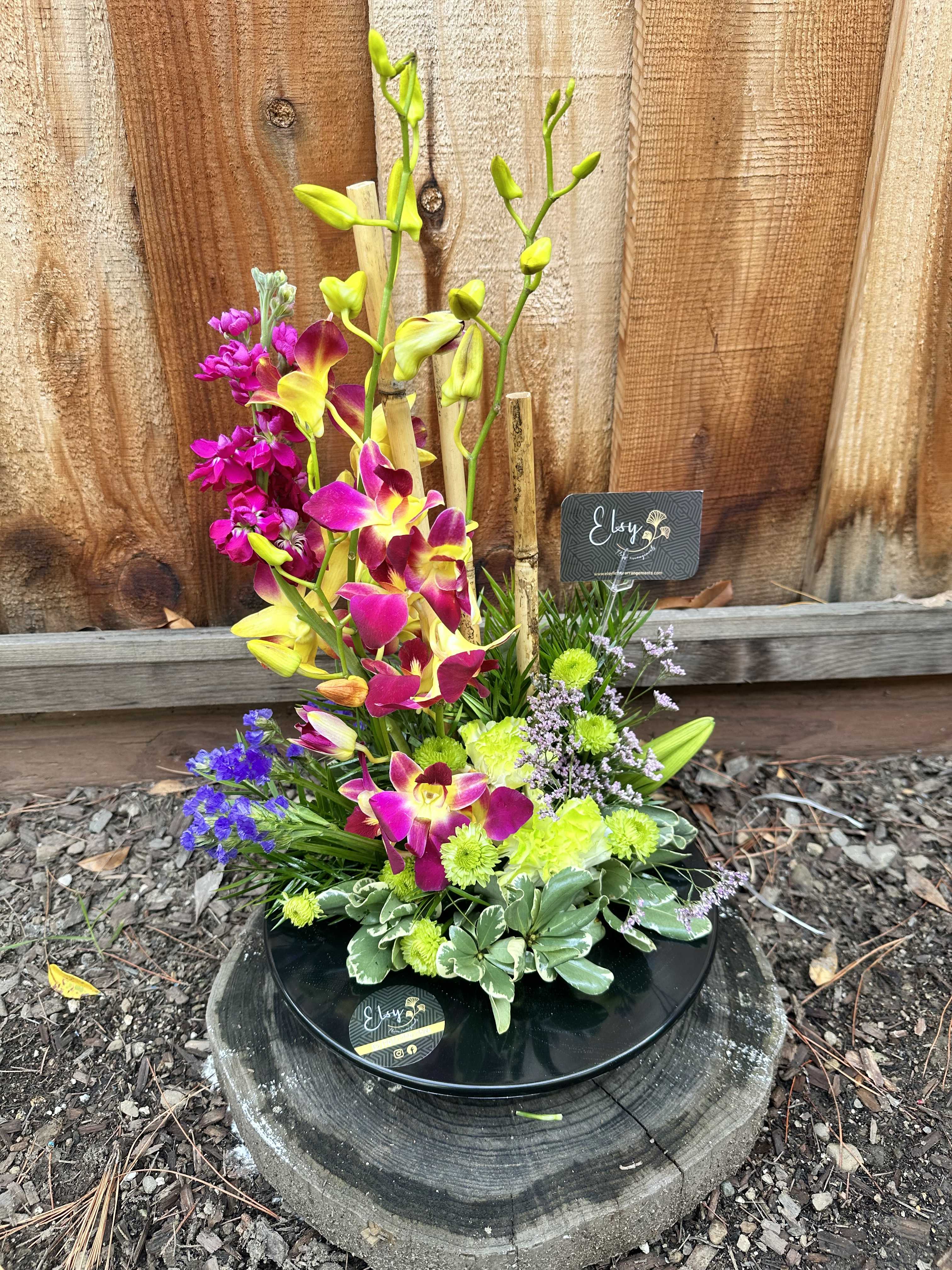 Colorful orchid arrangement in a black dish with mixed blooms