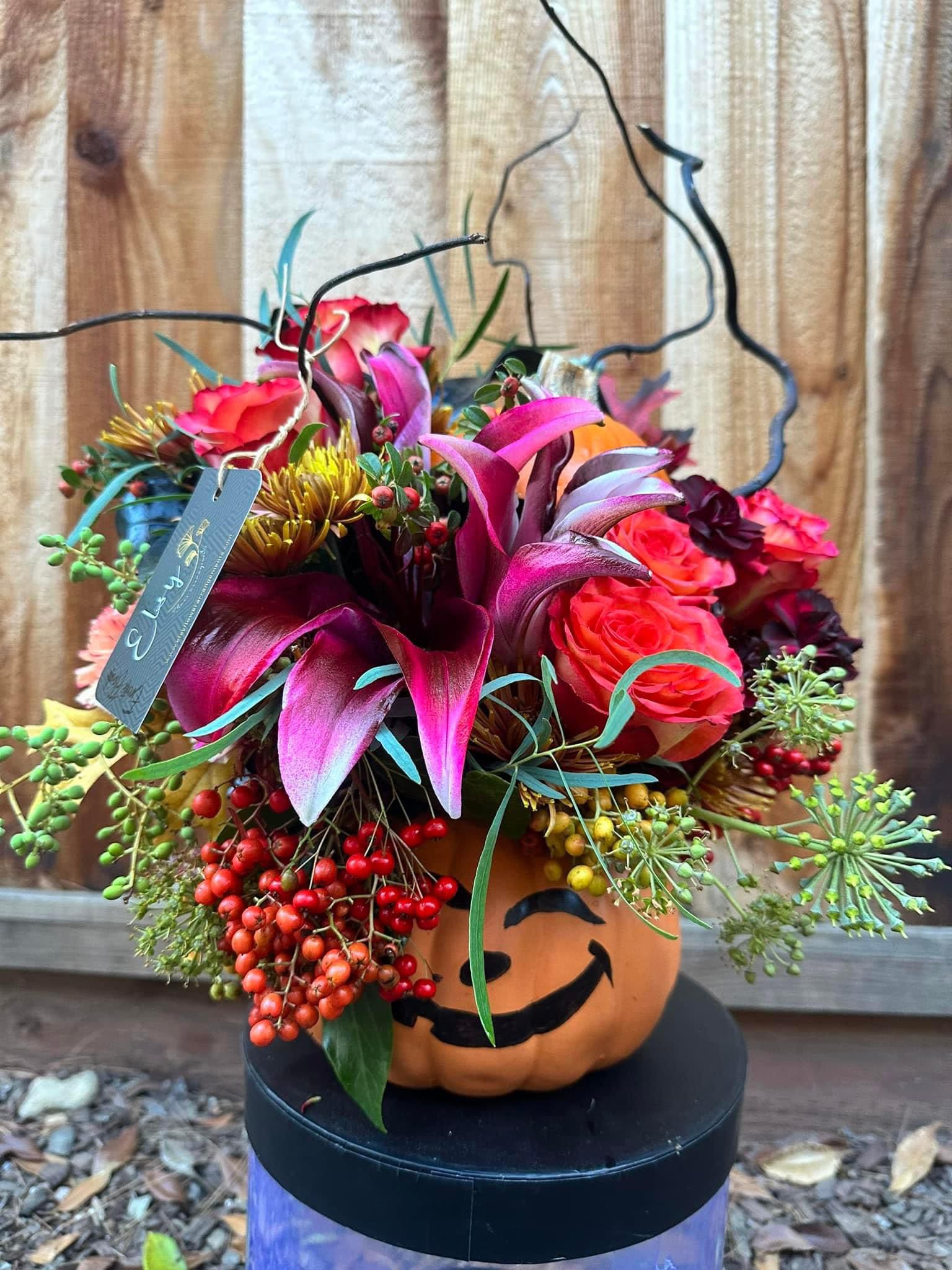 Halloween bouquet in a pumpkin container with pink and orange flowers