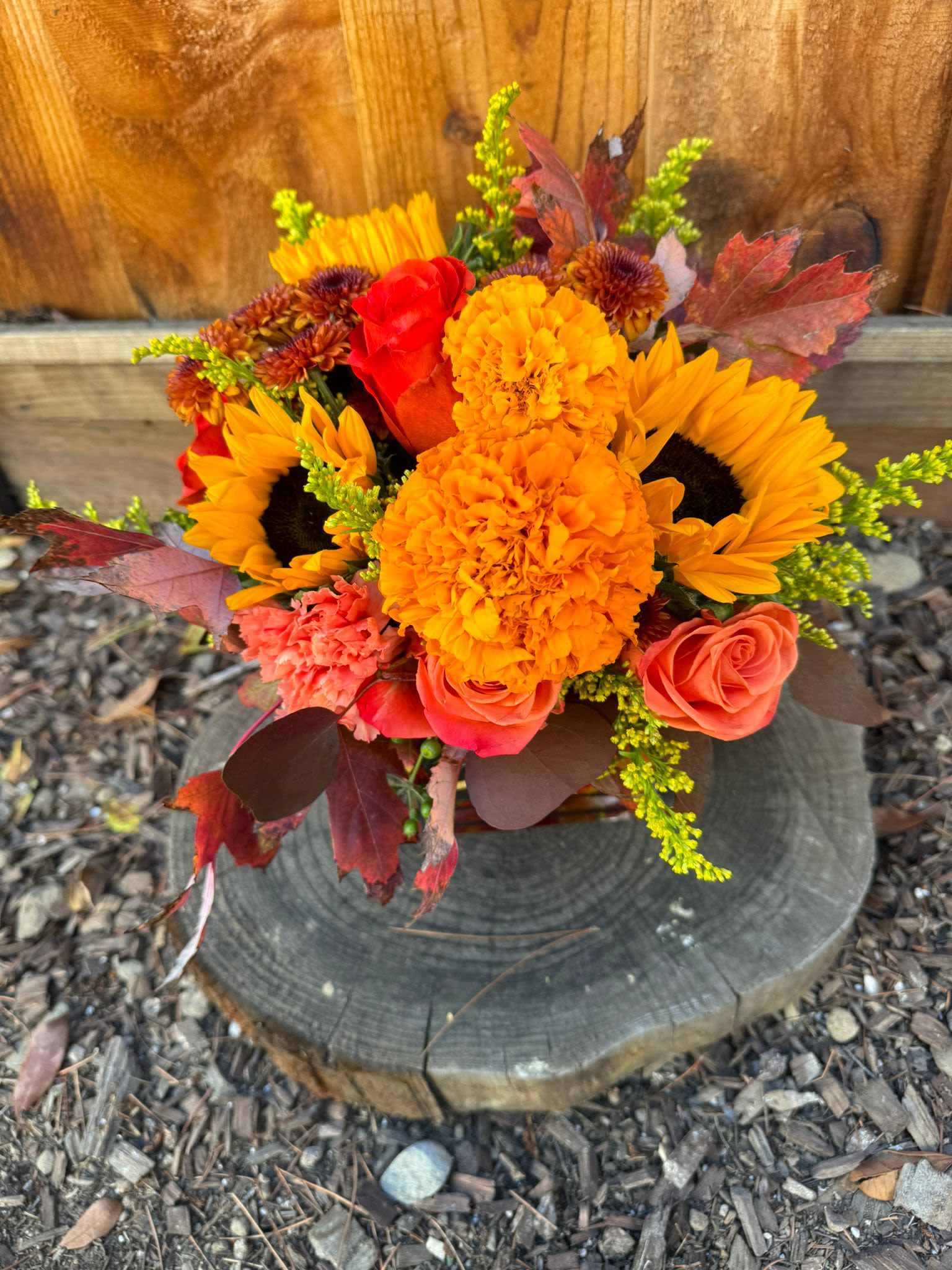 Bouquet of sunflowers, marigolds, and roses with autumn leaves