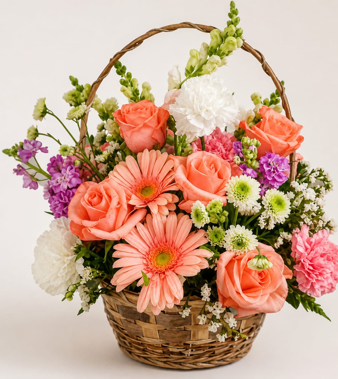 Basket arrangement of coral roses, pink daisies, and white blooms