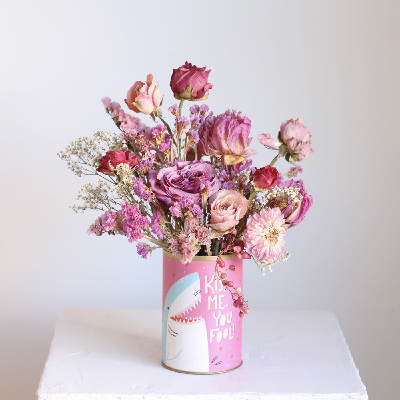 Pink and purple dried flower bouquet in a decorated tin can