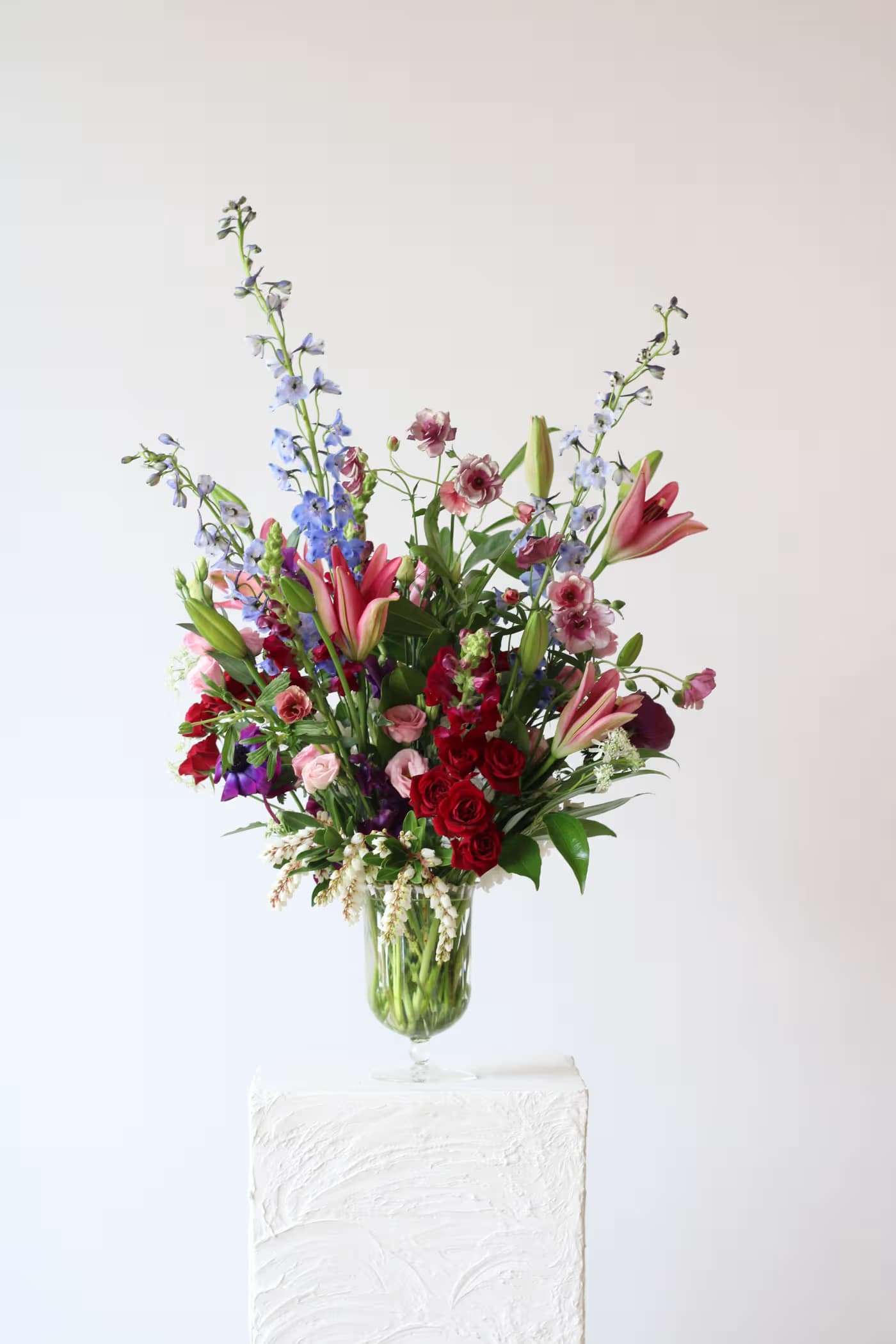 Tall mixed flower arrangement in a clear glass vase