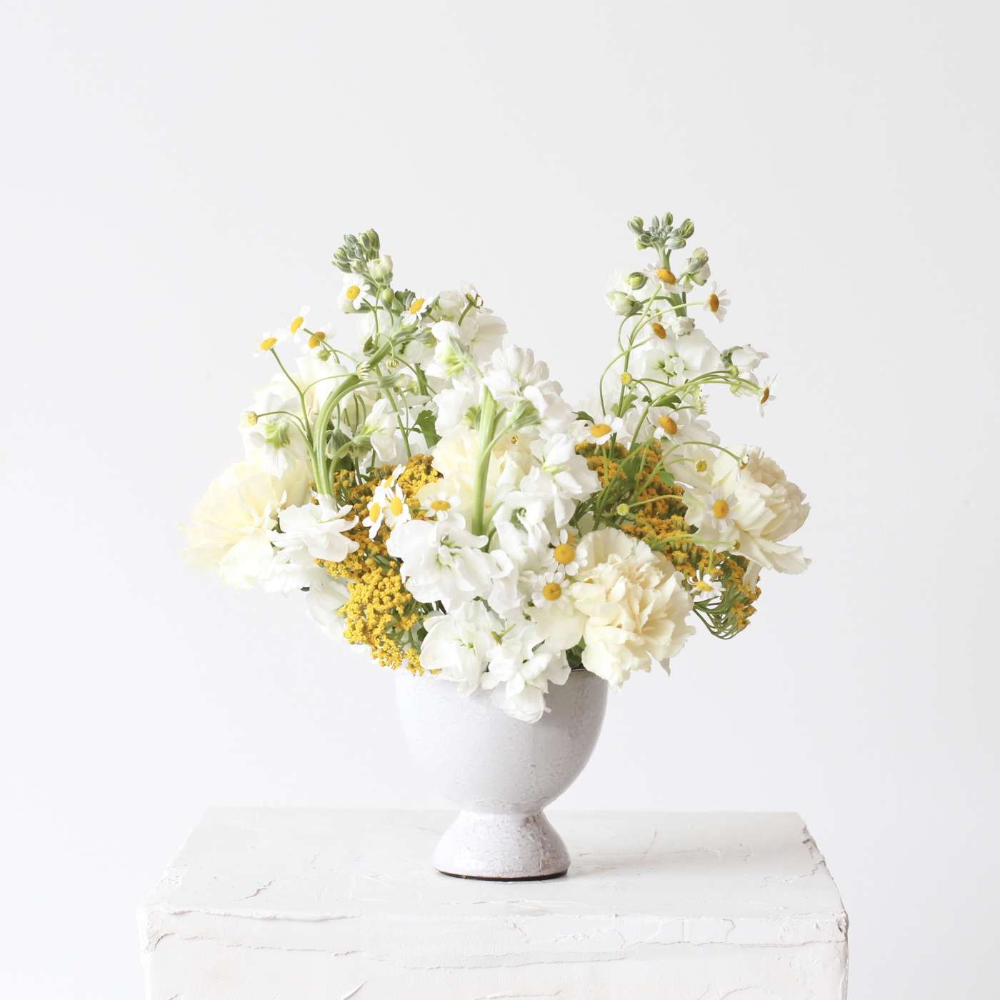 White and pale yellow flowers arranged in a gray vase