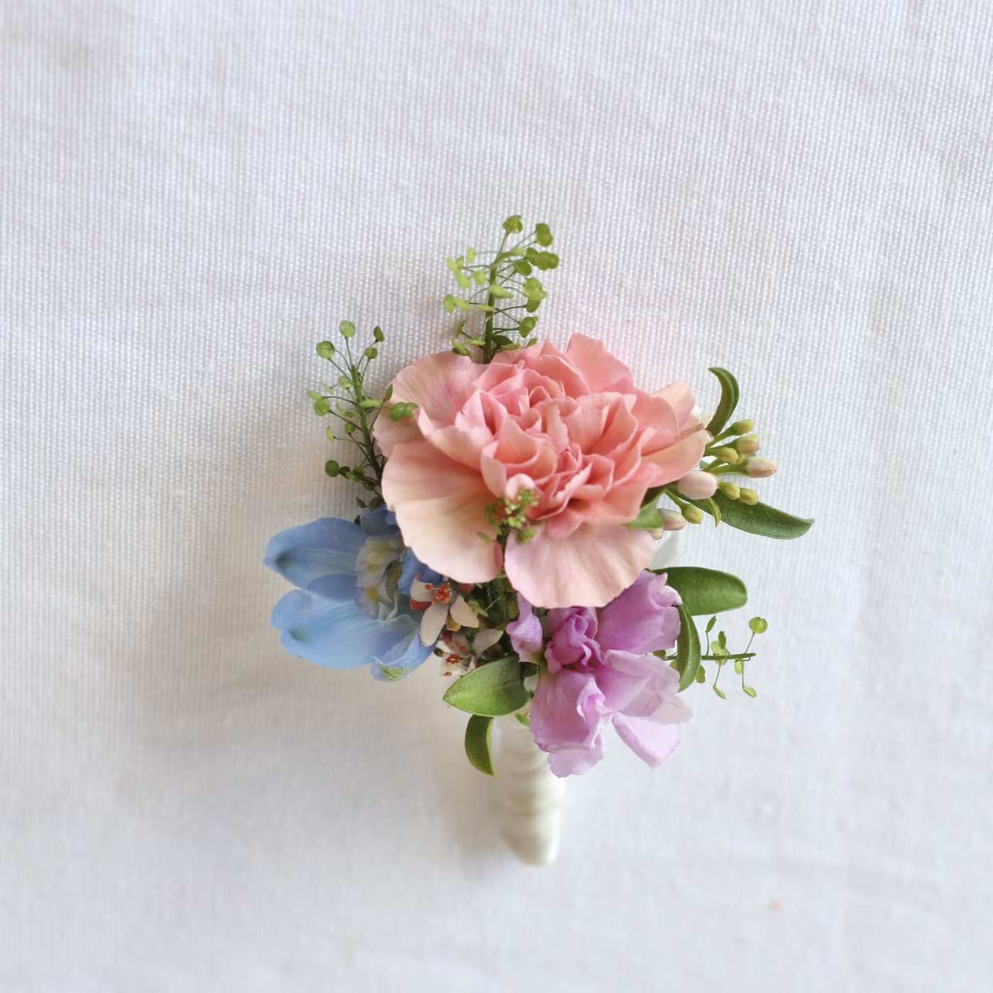 Small pink and blue floral boutonniere with green accents