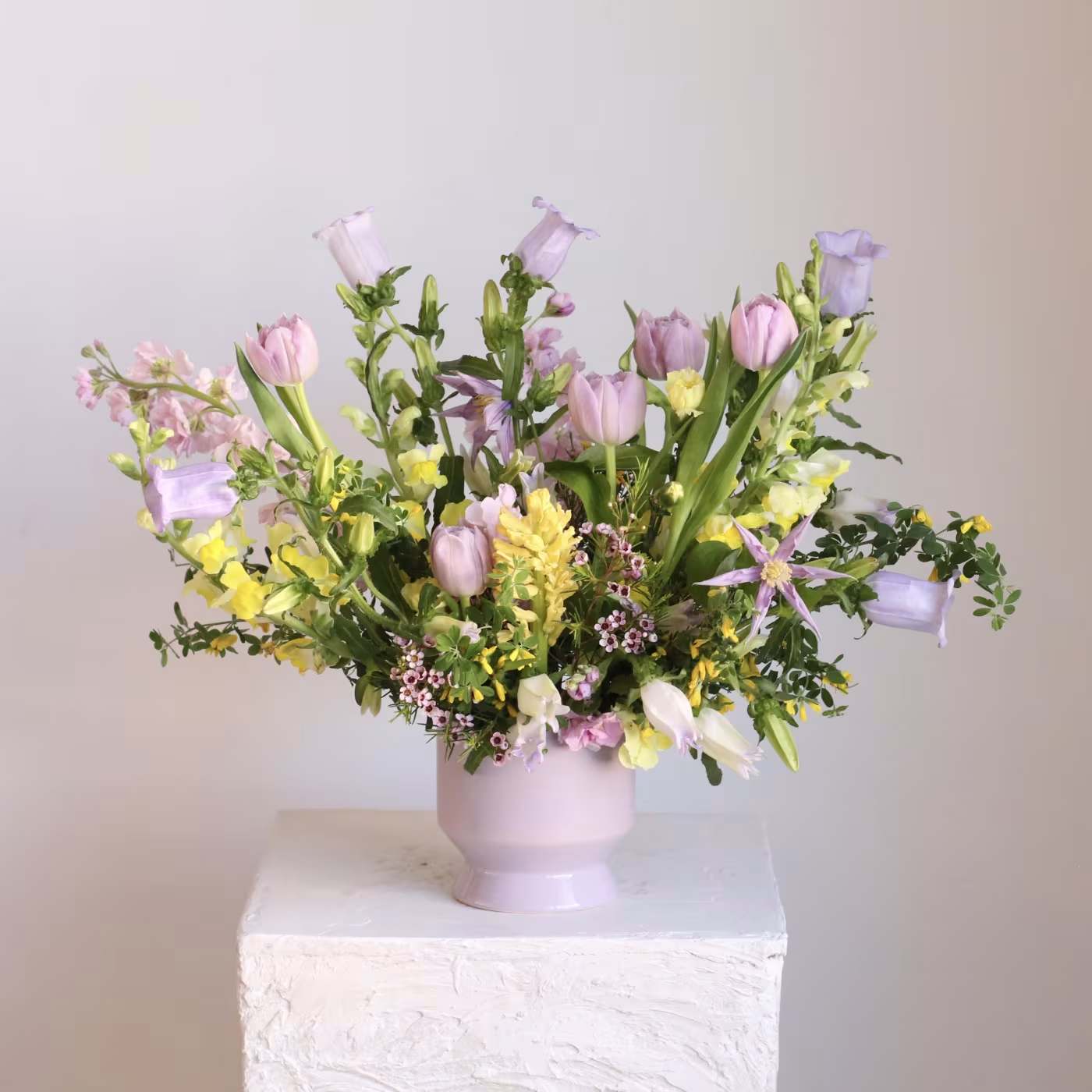 Pastel floral arrangement in a pink vase with tulips and bell-shaped blooms