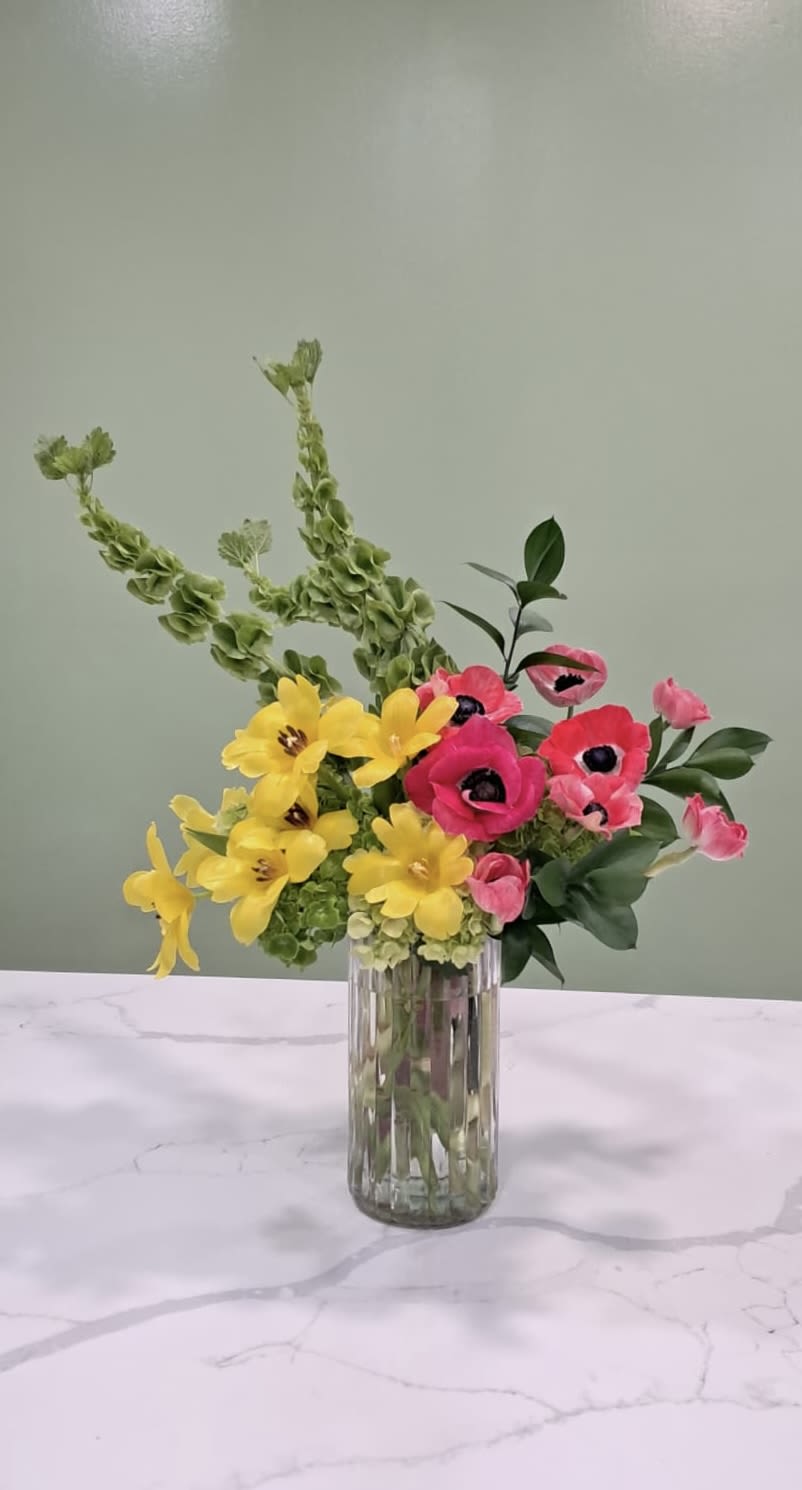 Bright yellow and pink flowers in a clear glass vase