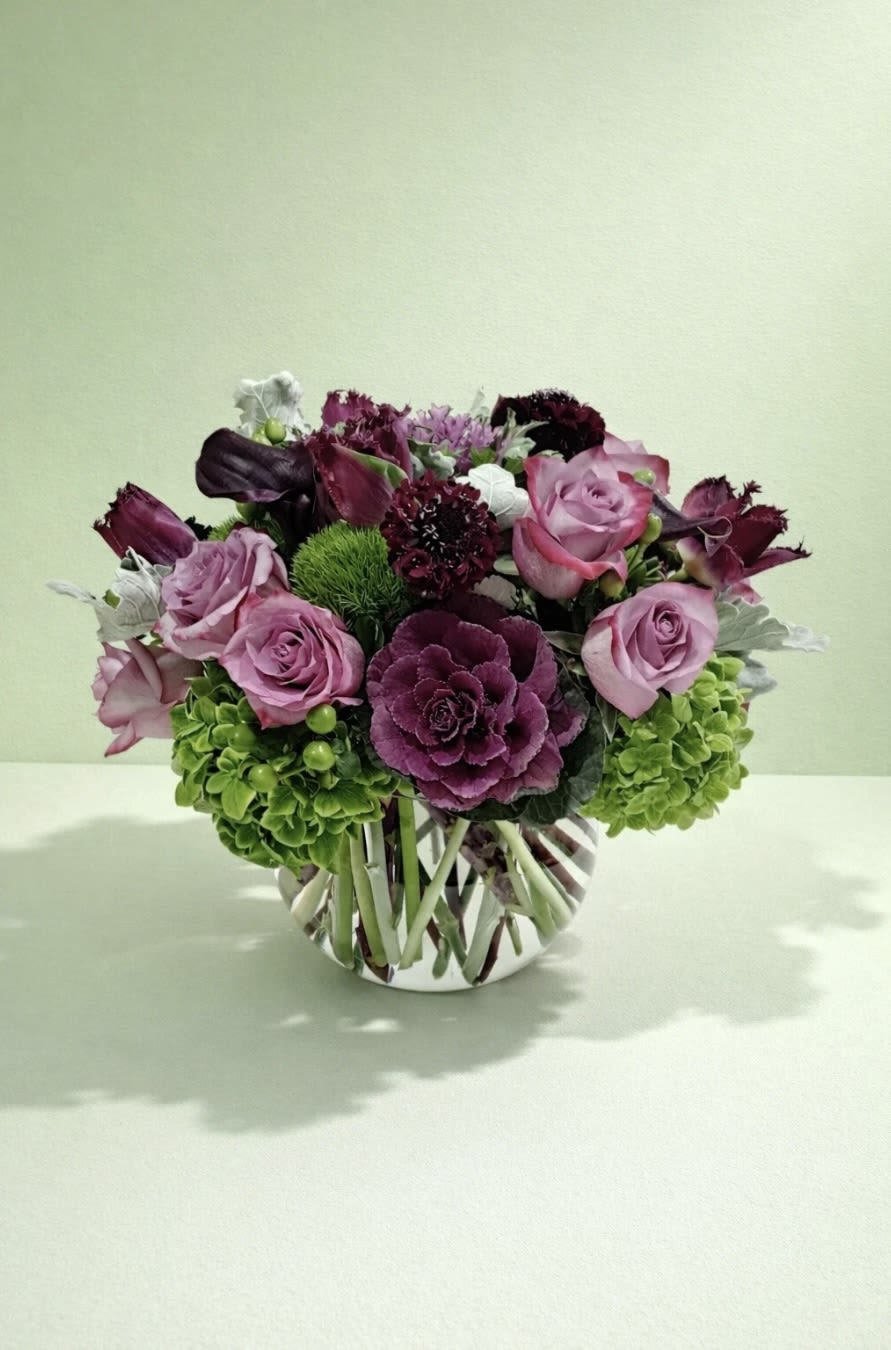 Pink and purple rose arrangement in a striped glass vase