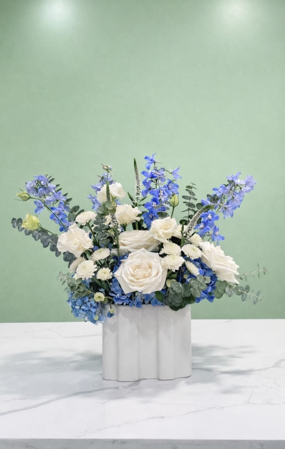 Blue and white floral arrangement in a white container