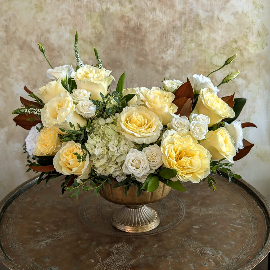 Cream and pale yellow roses arranged in a pedestal bowl