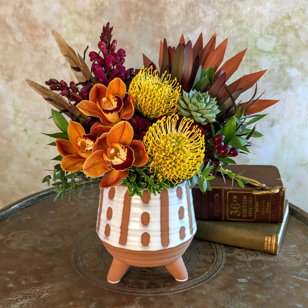 Orange orchids and yellow pincushion blooms in a patterned ceramic pot