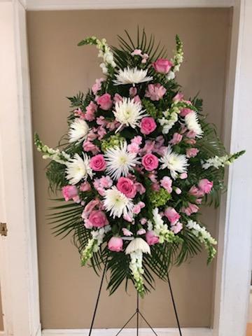 Standing floral spray with pink and white flowers on a black easel