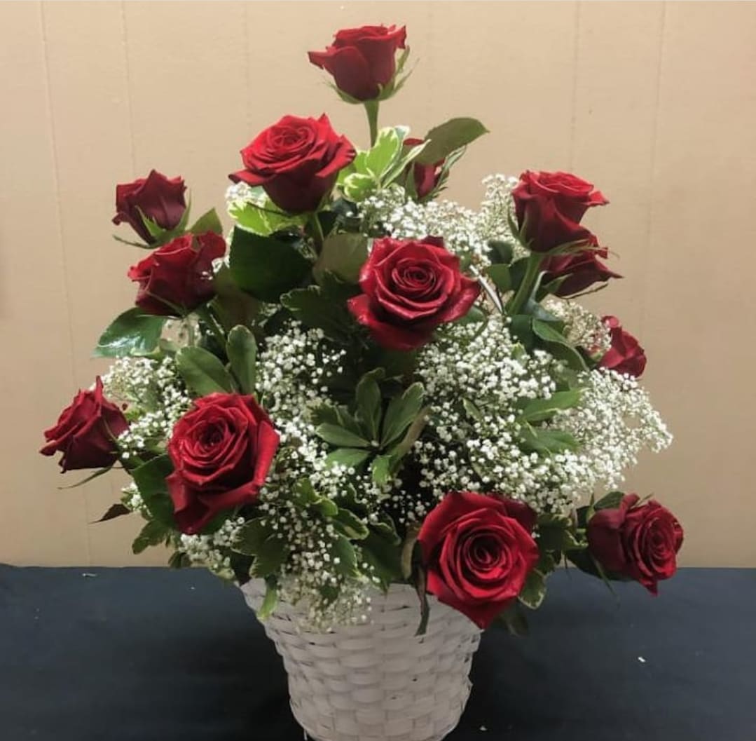 Red roses arranged in a white basket with baby's breath