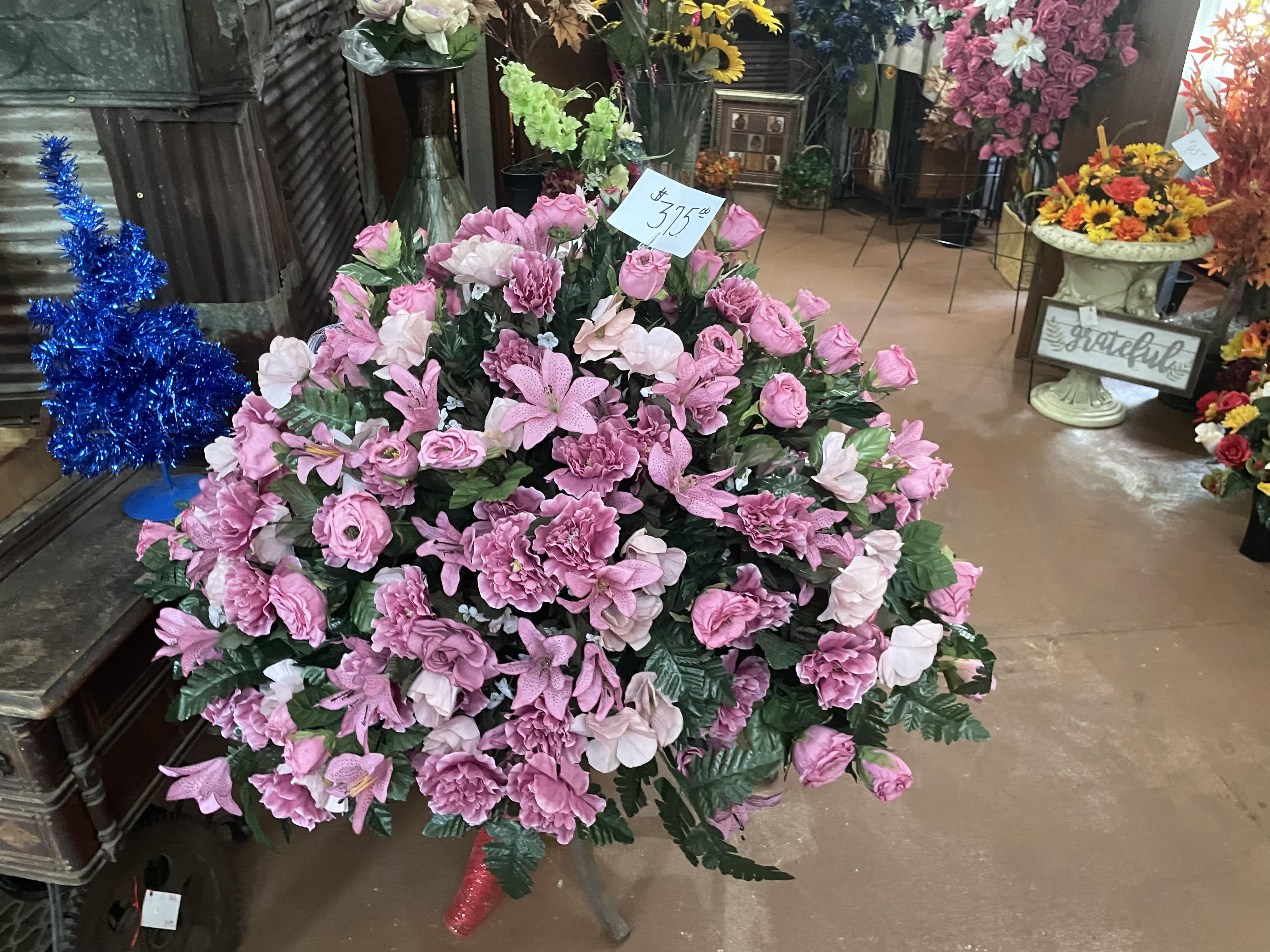Large pink floral arrangement with roses and lilies in a shop display