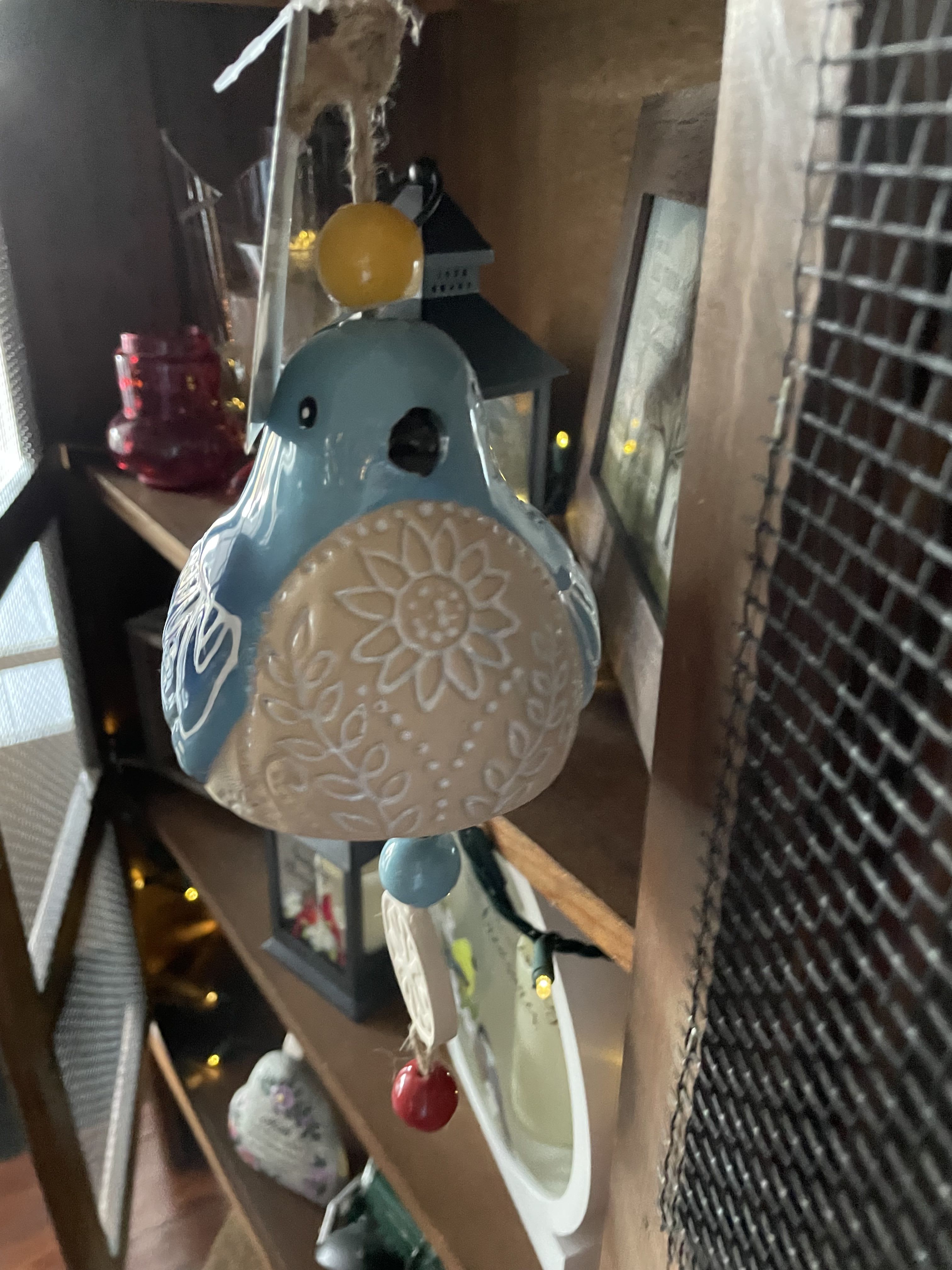 Blue Bird Windbell - AVAILABLE 5/5/25 - 5/12/25 ONLY This bird is super cute and a perfect gift.  We will send wrapped for home . Painted ceramic.  This bell features a blue bird with white floral details. Hanging underneath are of beads and round discs.  Overall Length:  Dimensions: 17.75" H x 4" W x 4.5" D