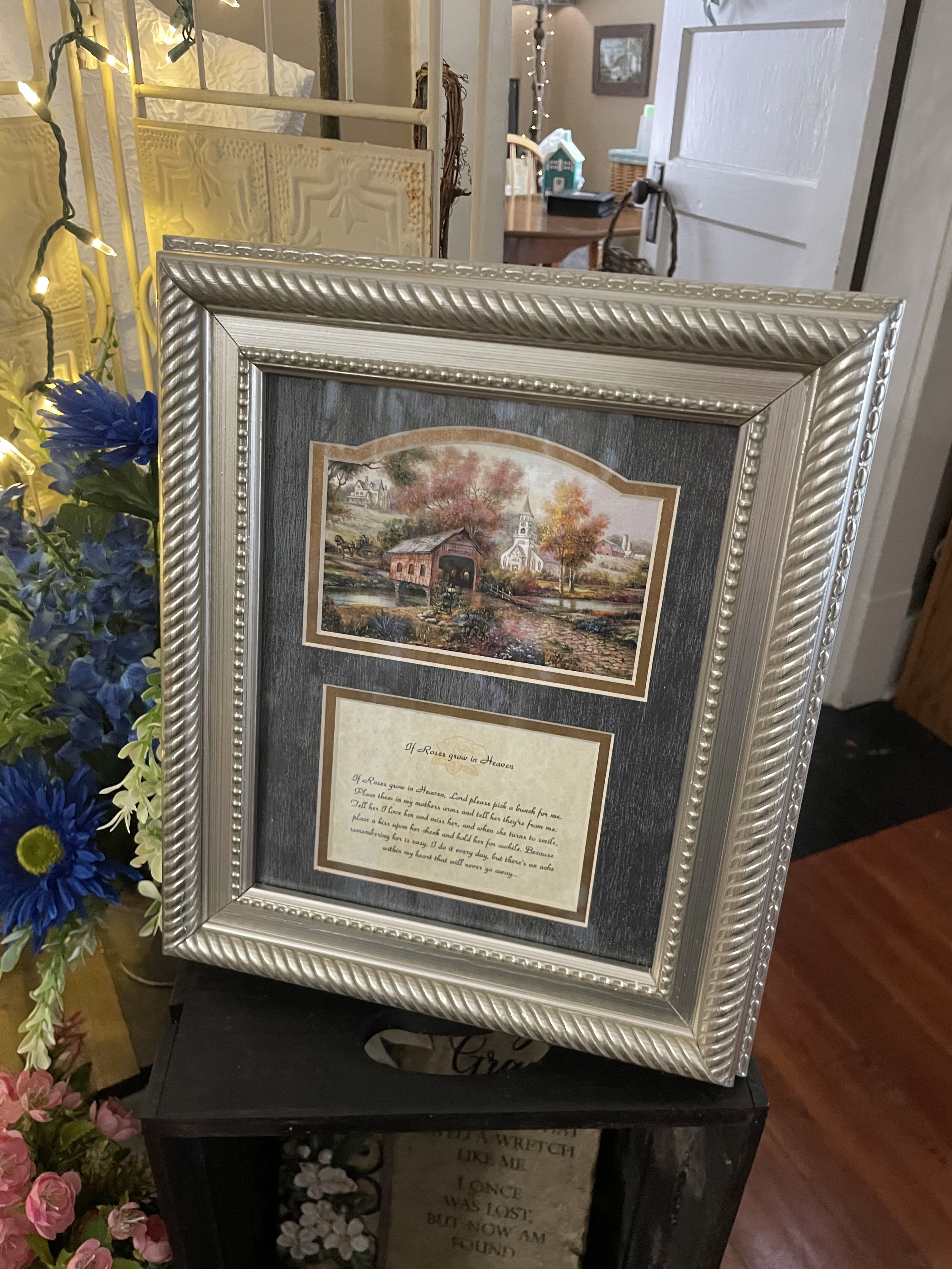 Framed memorial print with blue and pink flowers beside it