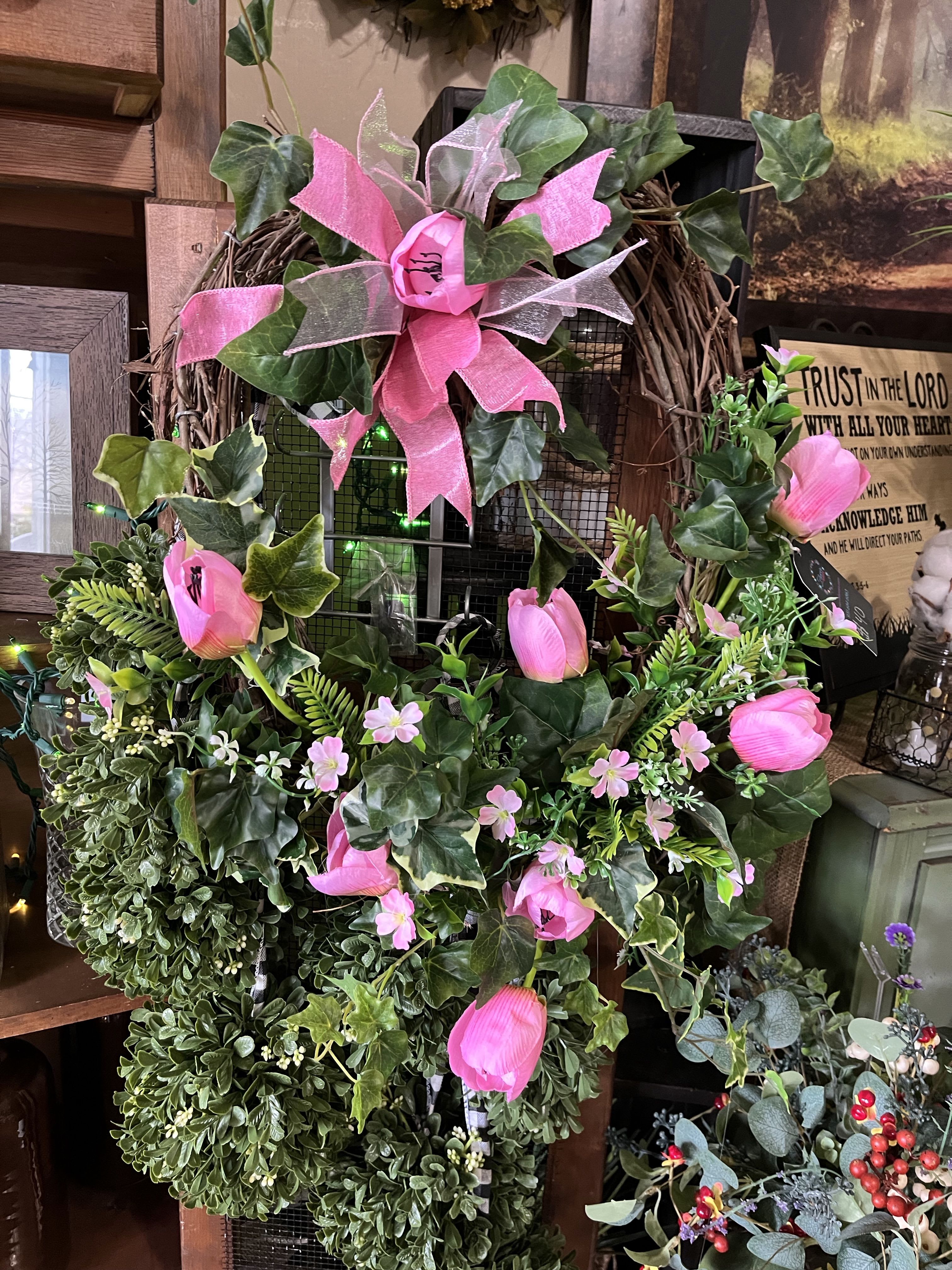 Pink tulips and ivy arranged on a grapevine wreath with a ribbon bow