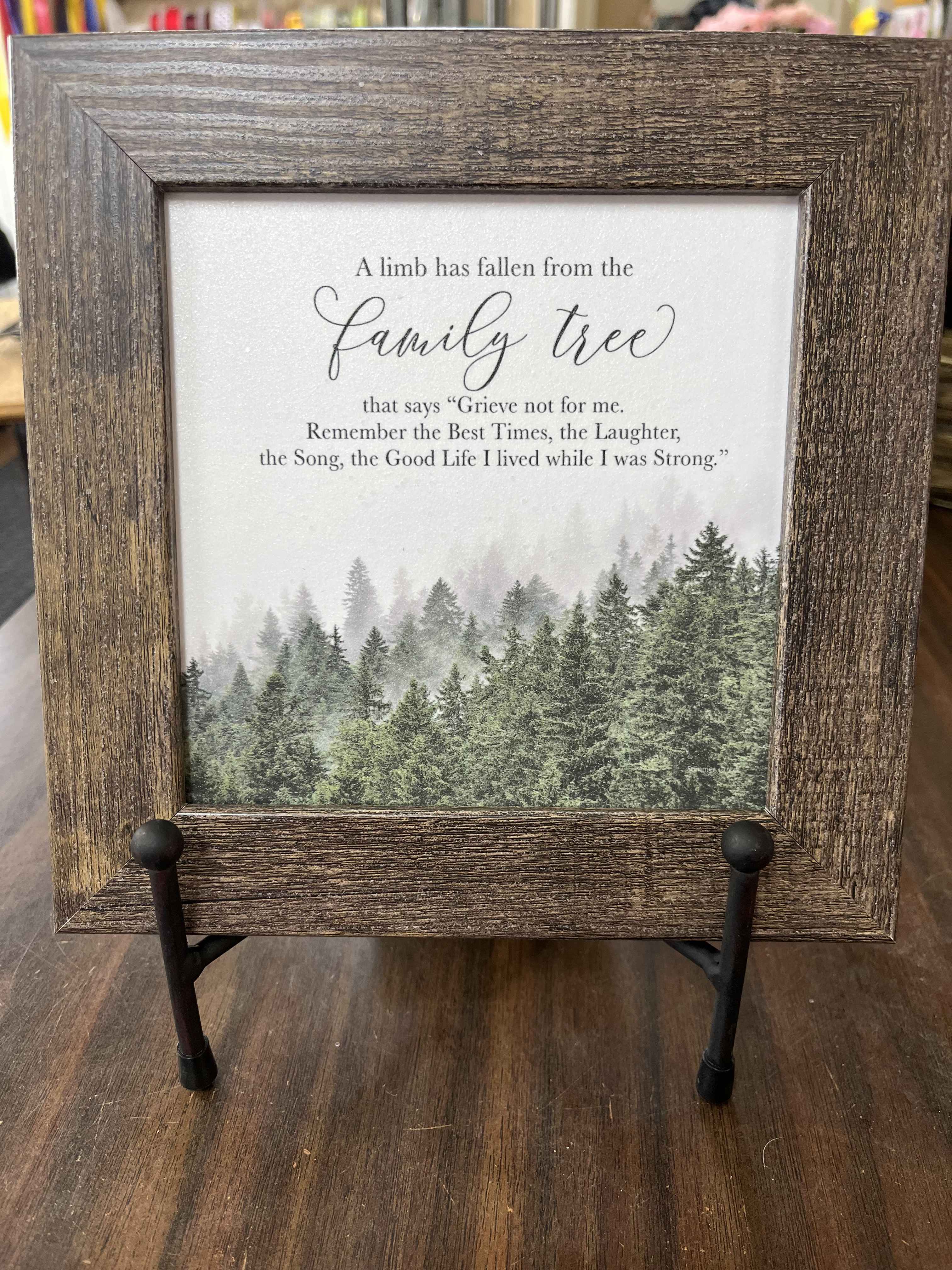 Framed memorial sign with a forest scene and text about a family tree