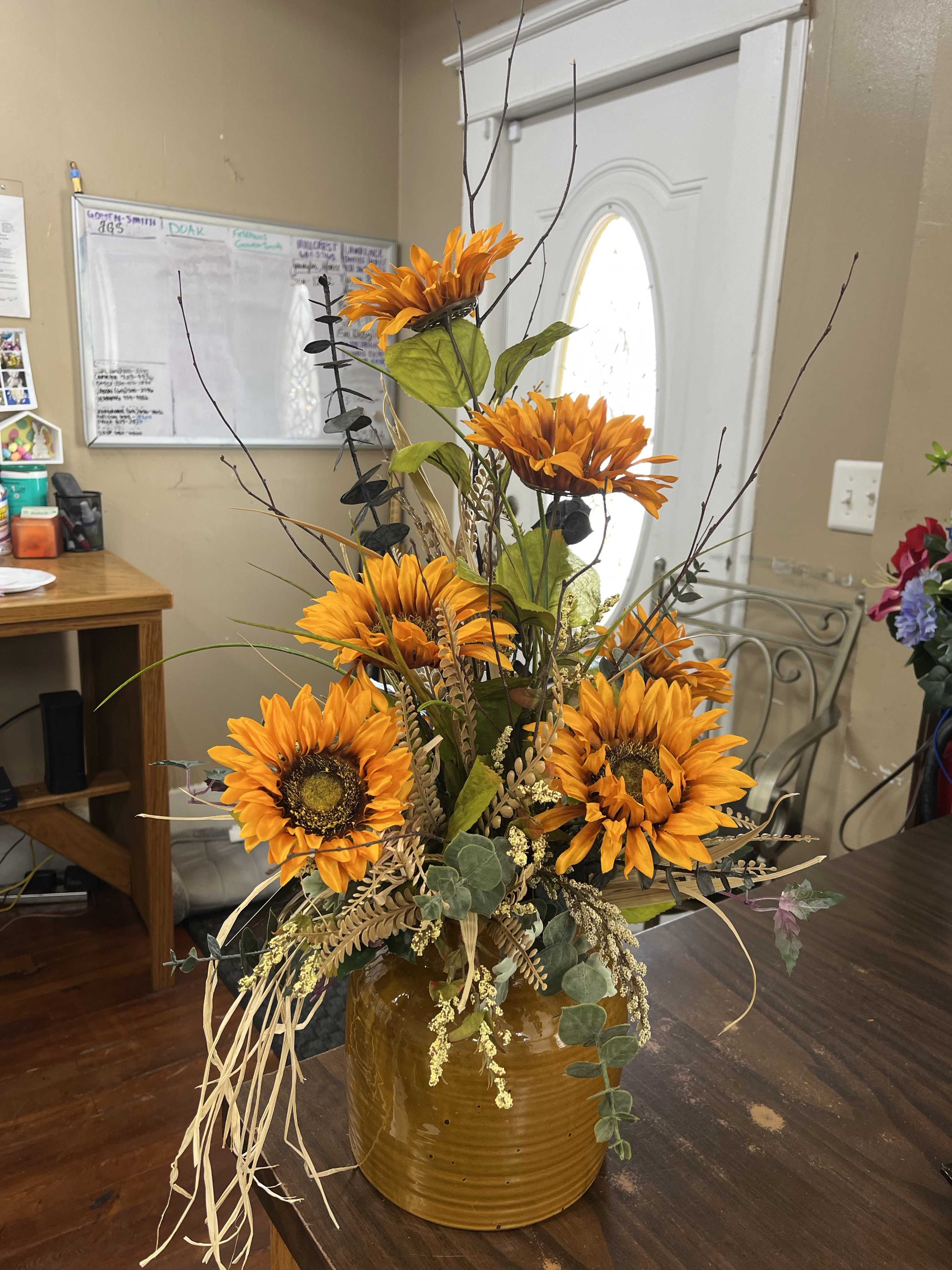 Orange sunflower arrangement in a brown ceramic vase